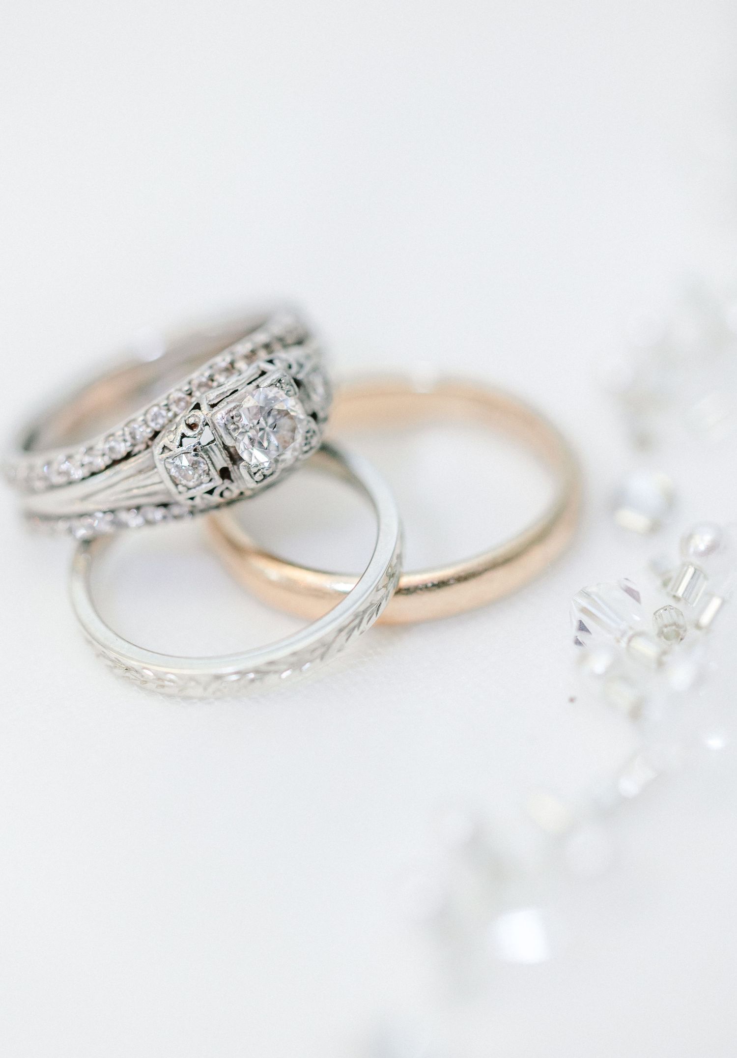 Close-up of delicate diamond wedding rings on white surface with intricate details.