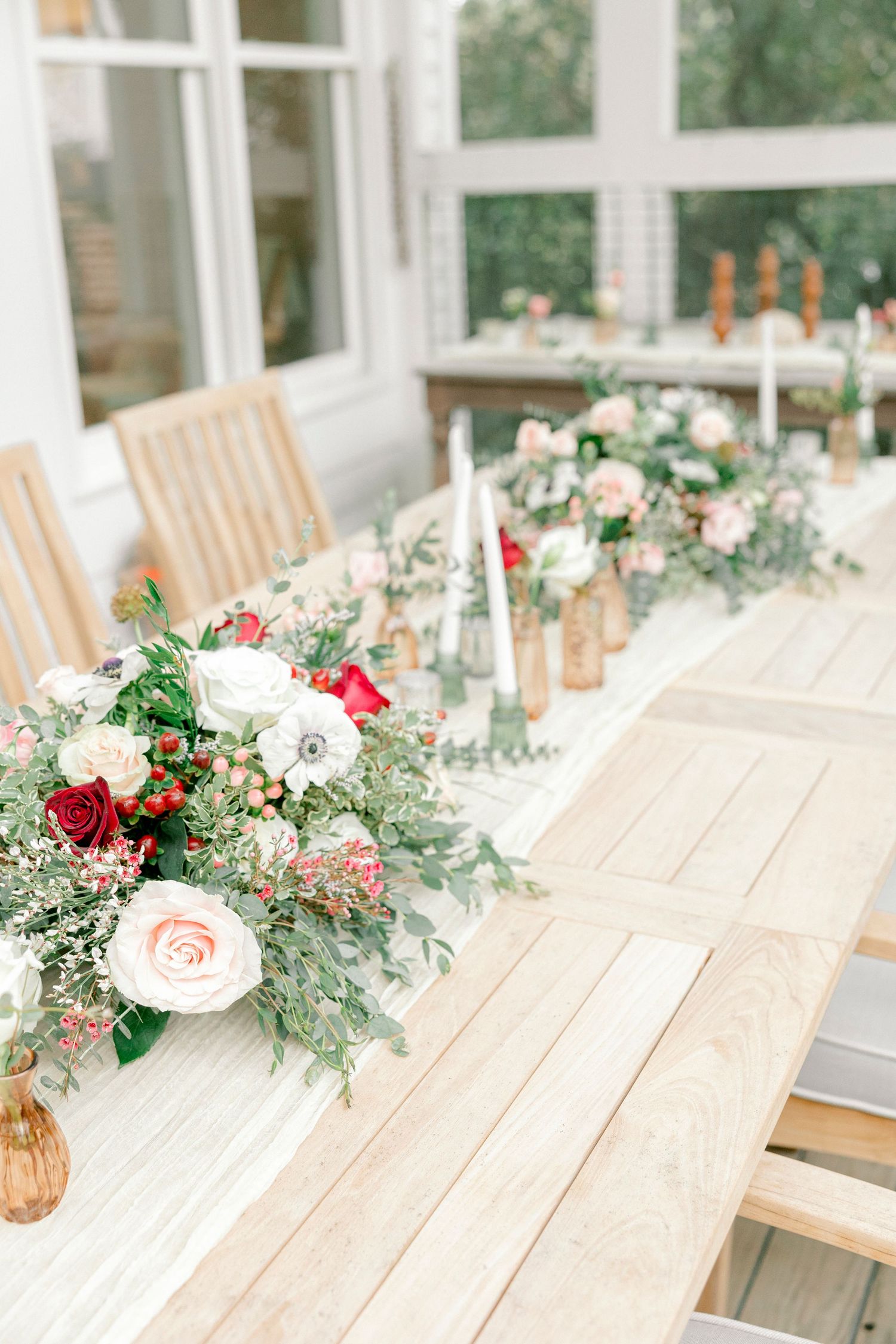 Elegant table setting with red and white floral centerpieces and gold accents.