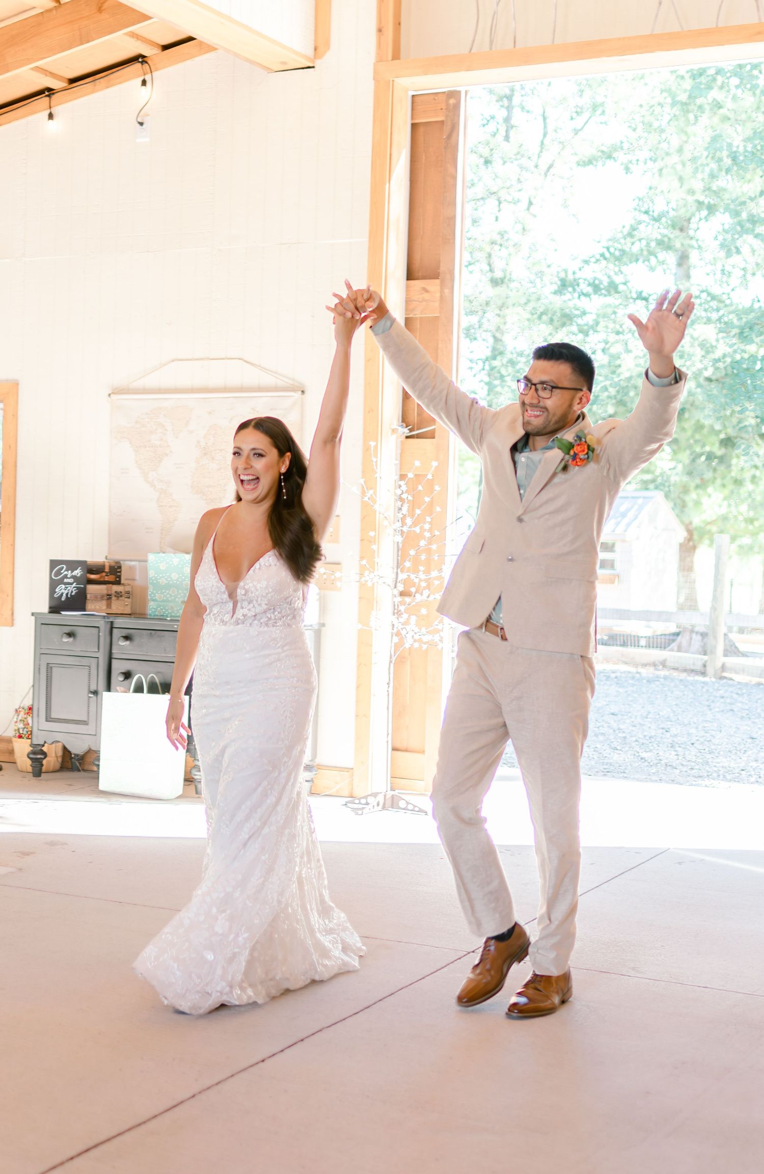 Joyful bride and groom in white dress and tan suit celebrate their wedding reception grand entrance.