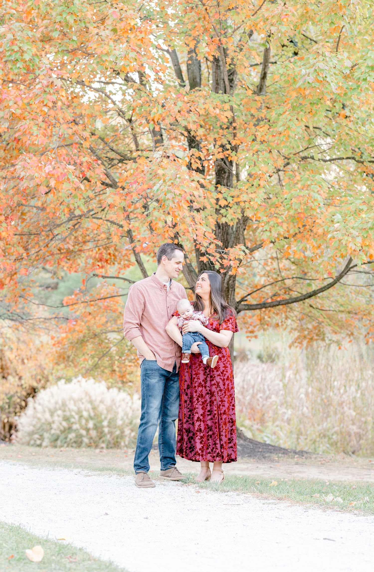 Couple shares a tender moment under vibrant autumn trees with orange and yellow foliage.