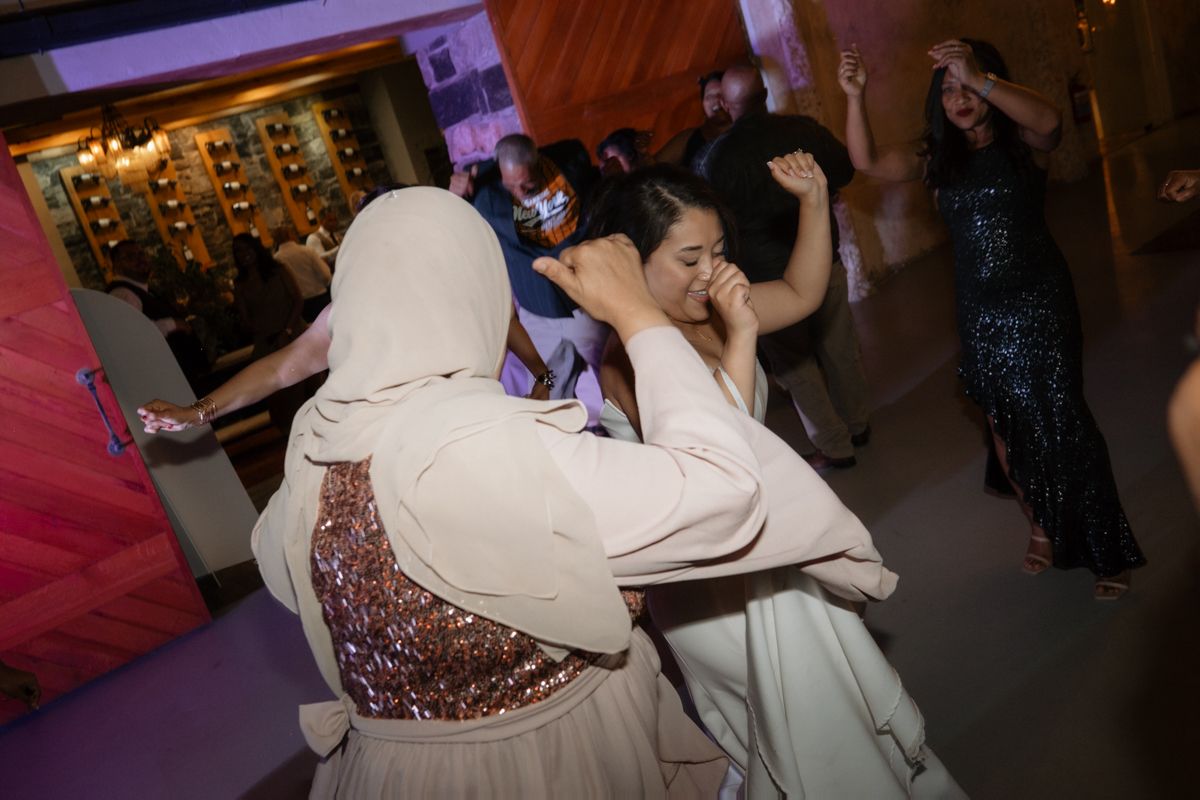 Guests in festive attire dance and laugh together on the wedding reception dance floor.