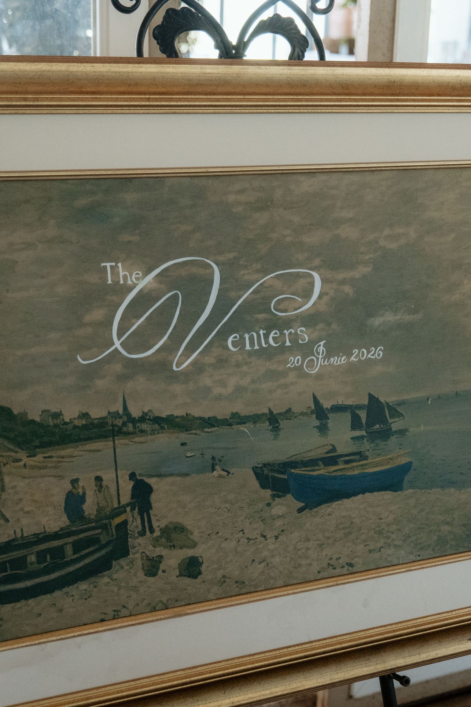 Framed wedding welcome sign reading The Venters 20 June 2026 with nautical painting background.