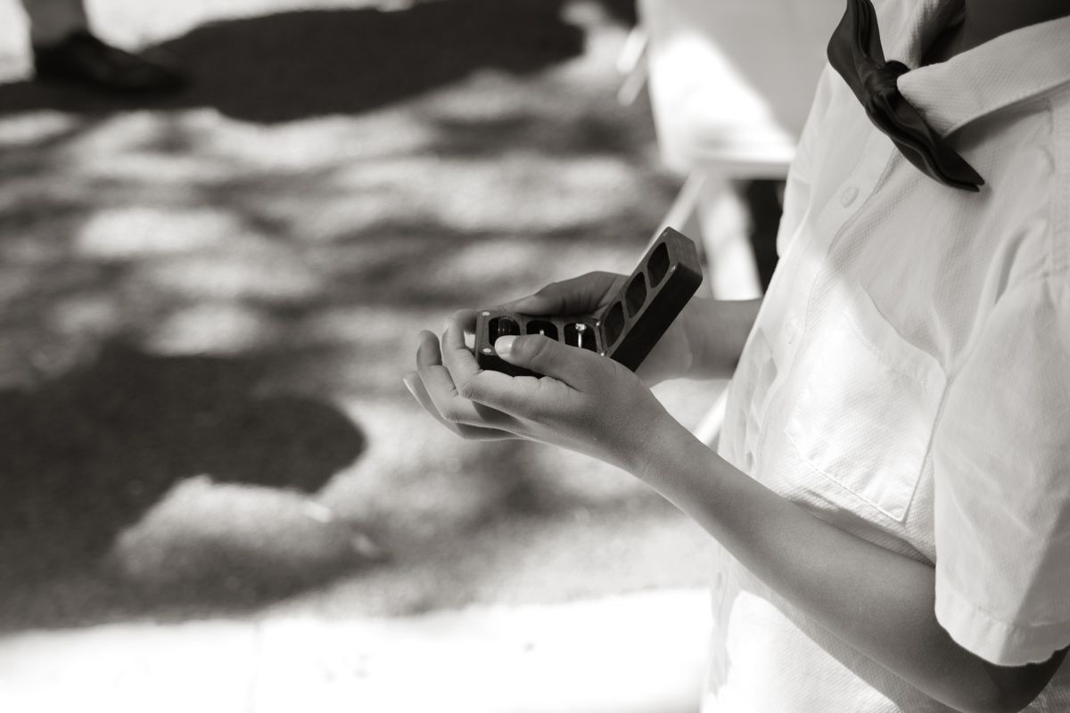 Close-up black and white photo of person in white shirt holding a smartphone outdoors.