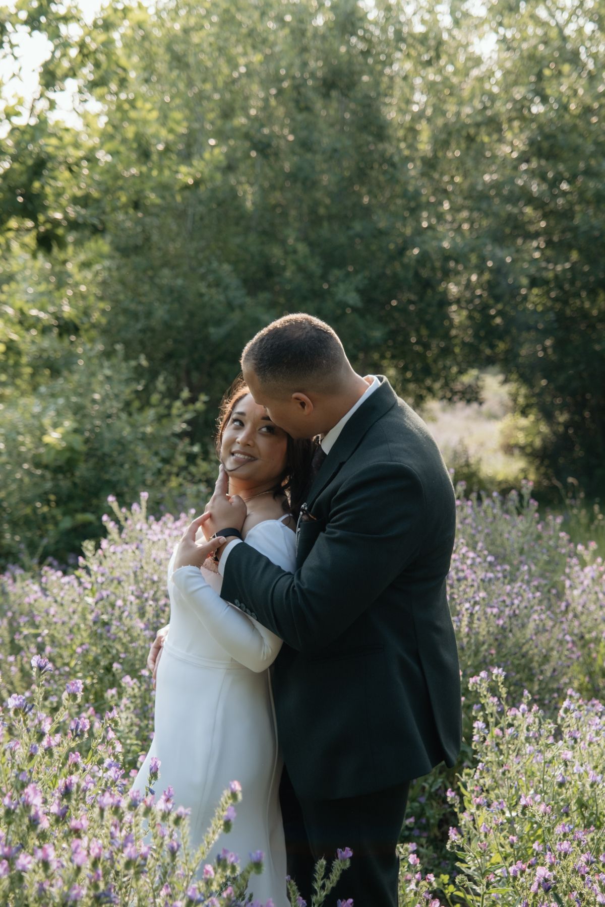 Bride and groom embracing romantically in lavender field during golden hour wedding portrait session.