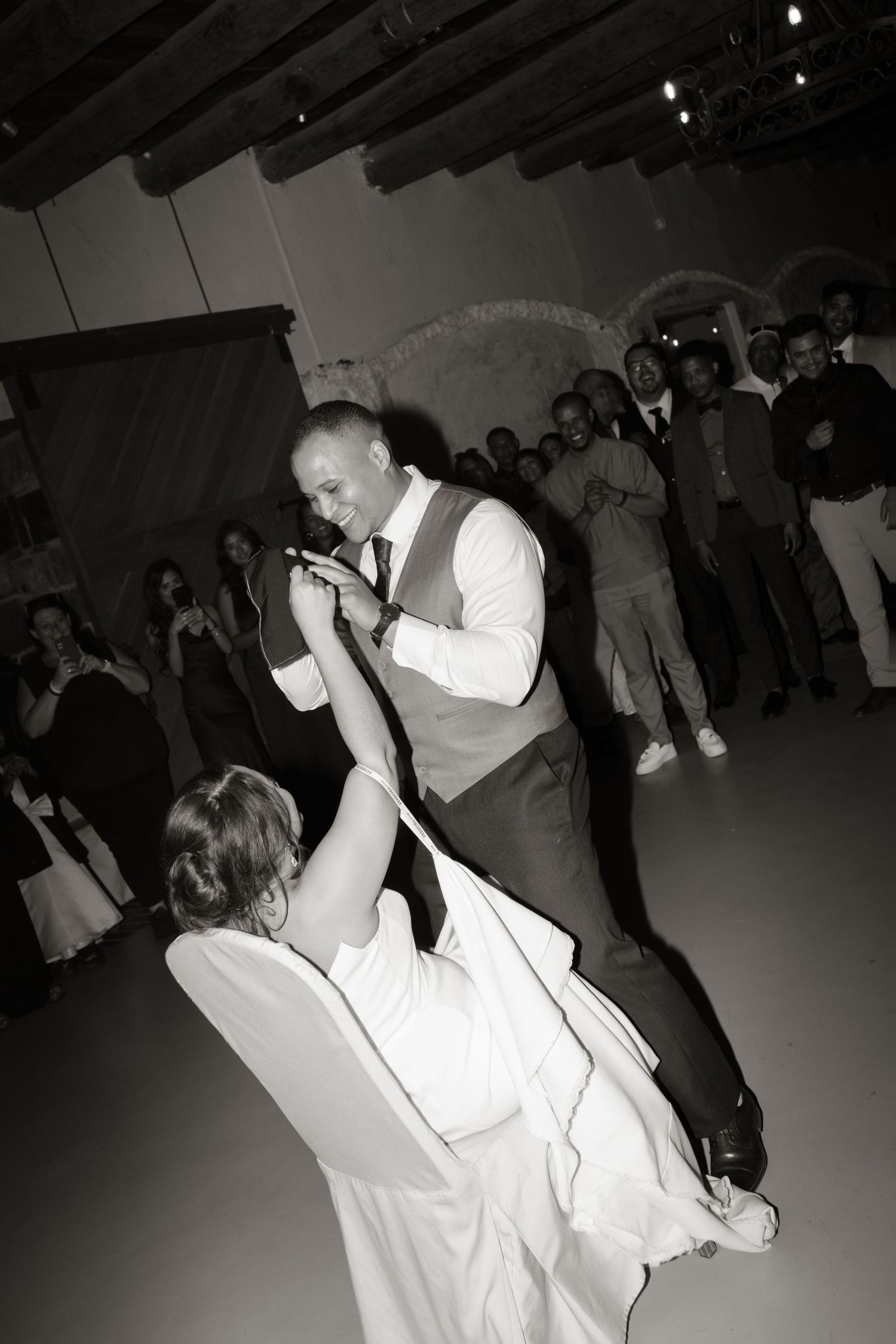 Bride and groom share a romantic first dance dip at their wedding reception in black and white.