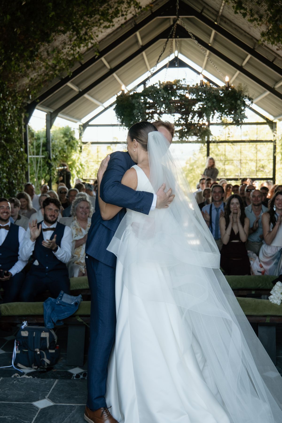Bride and groom share their first kiss at the altar in a stunning glass greenhouse wedding venue.