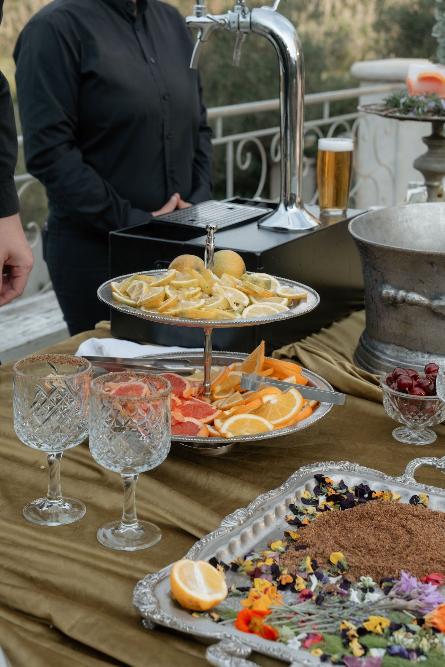 Elegant wedding cocktail hour display with crystal glasses, citrus fruits, and garnishes on table.