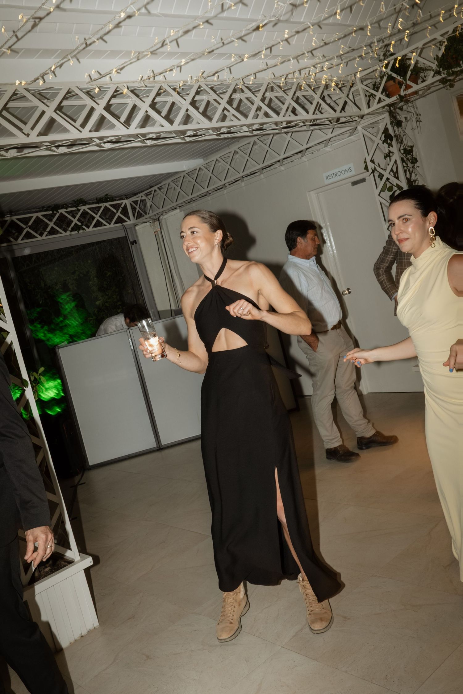 Guest in black dress dancing joyfully at an elegant indoor wedding reception.