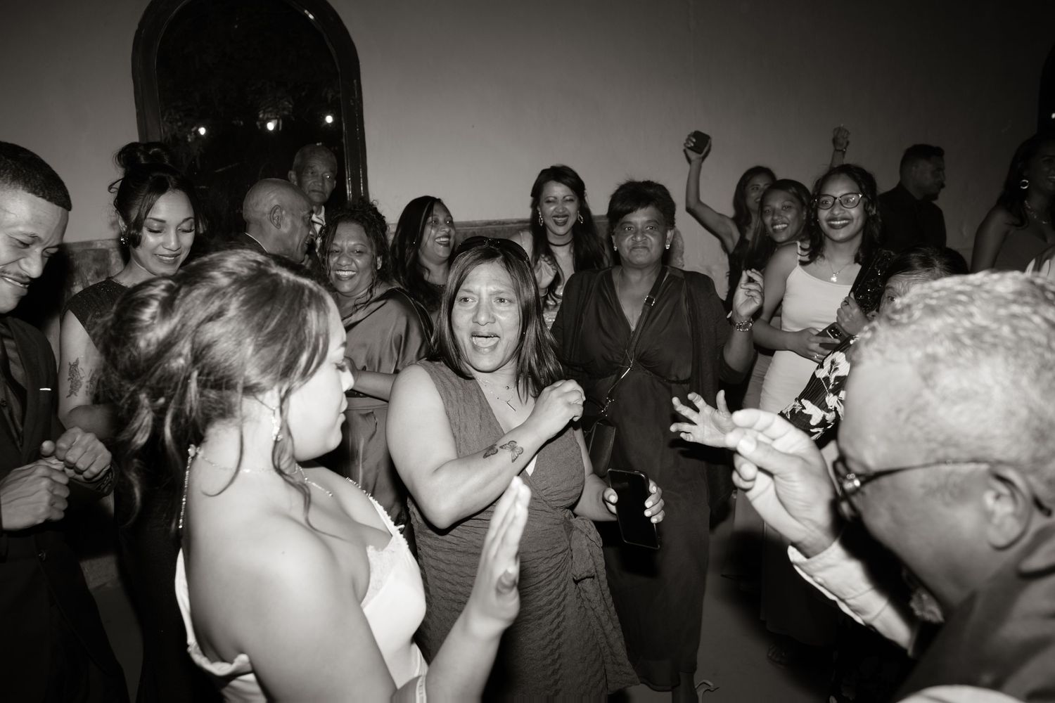 Guests dancing and celebrating joyfully at a wedding reception in black and white photography.