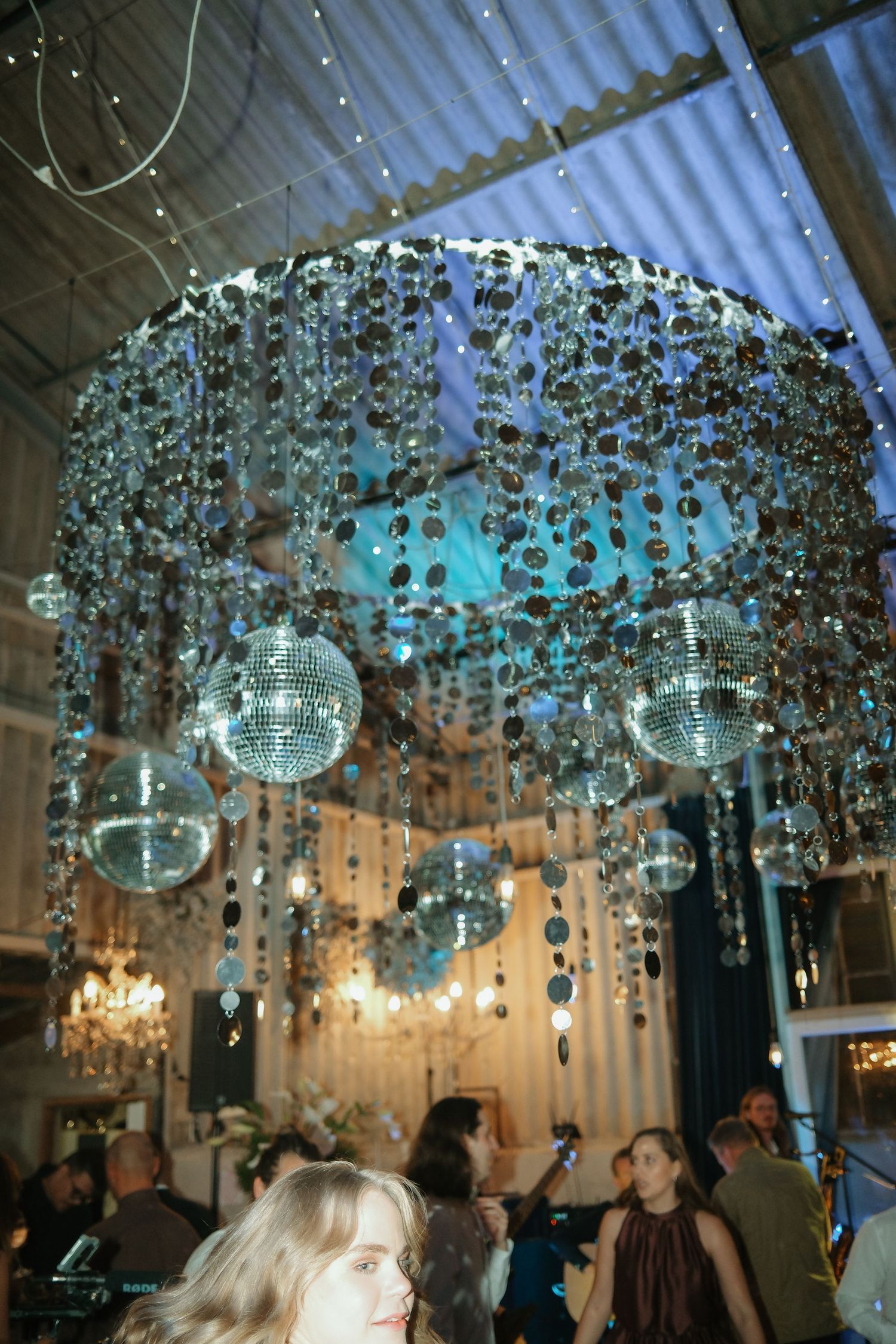 Elegant crystal chandelier with hanging disco balls illuminating a lively indoor party event.