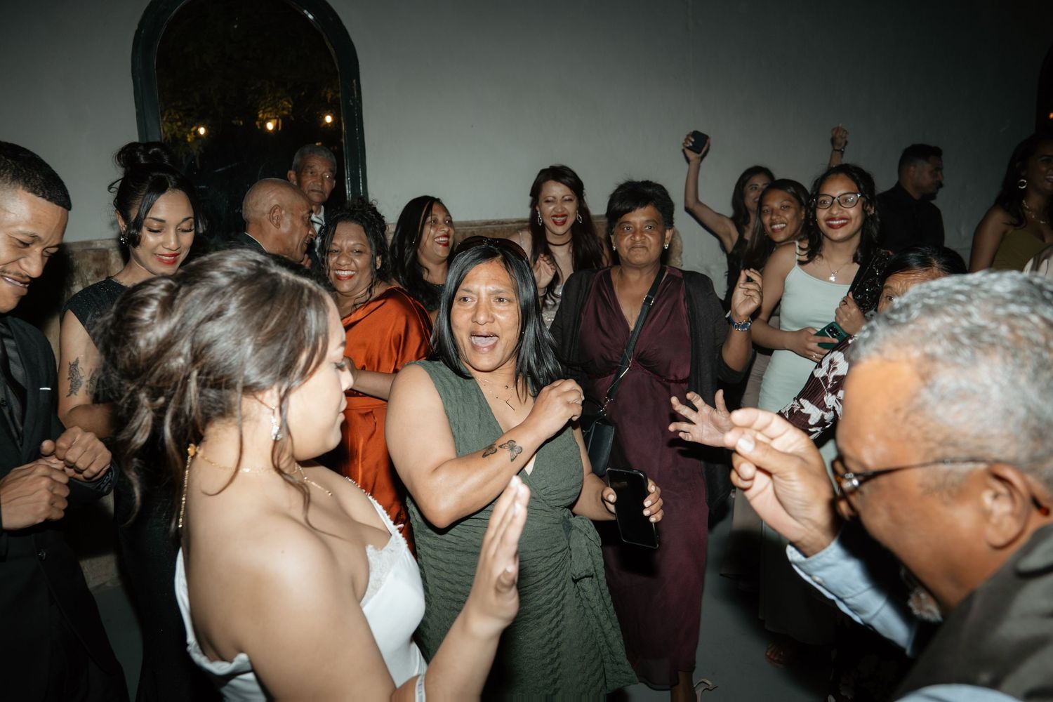 Joyful wedding reception guests dancing and celebrating together indoors.