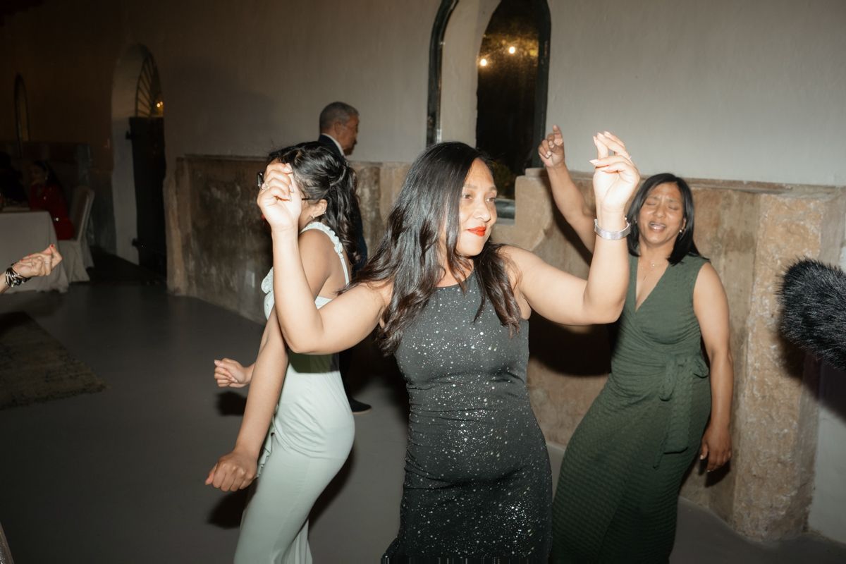 Wedding guests dance joyfully on the dance floor during a lively wedding reception celebration.