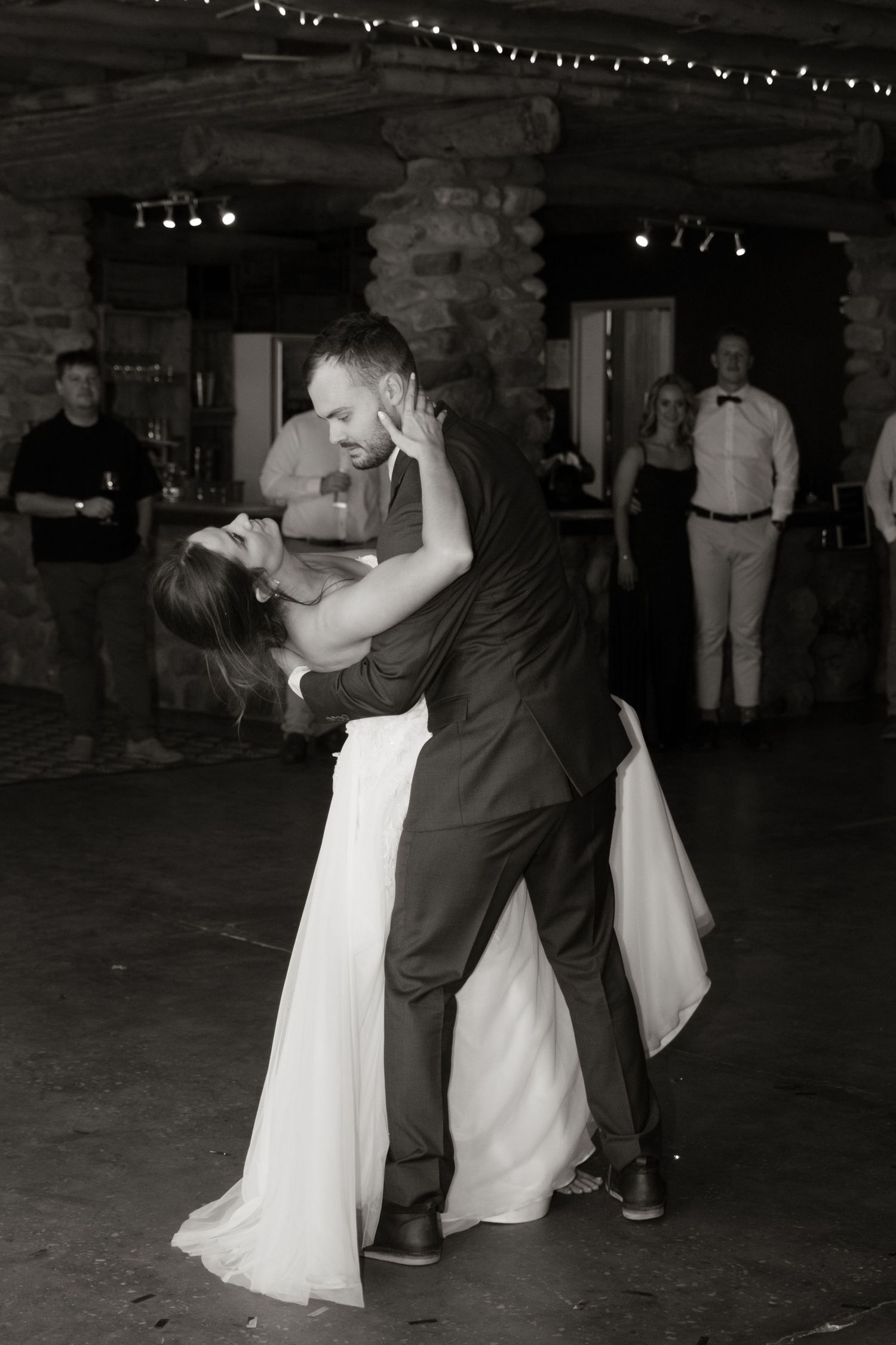 Black and white photo of bride and groom sharing a romantic dip dance at their wedding reception.