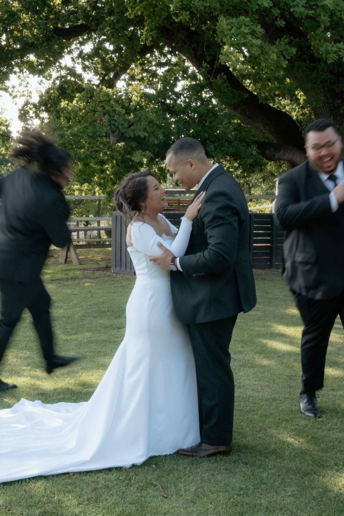 Bride and groom share romantic moment on green lawn as wedding guests move around them outdoors.