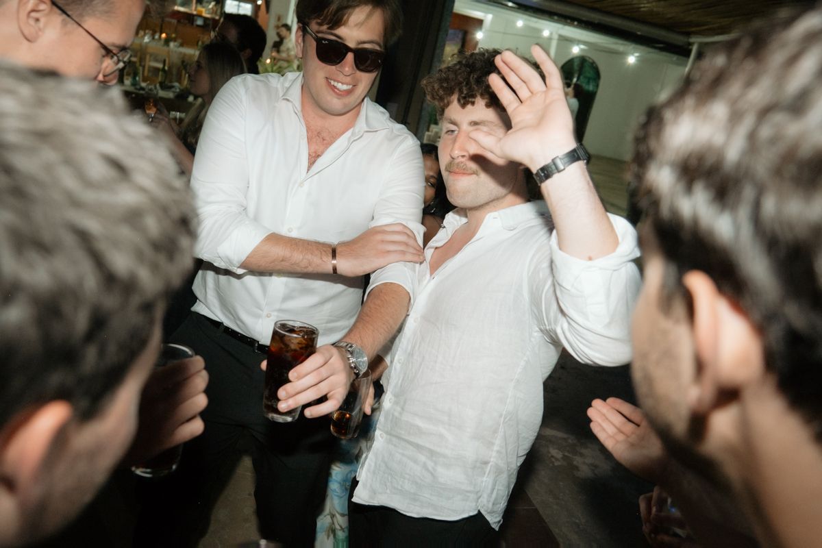 Two male wedding guests dancing and celebrating together at lively wedding reception party.