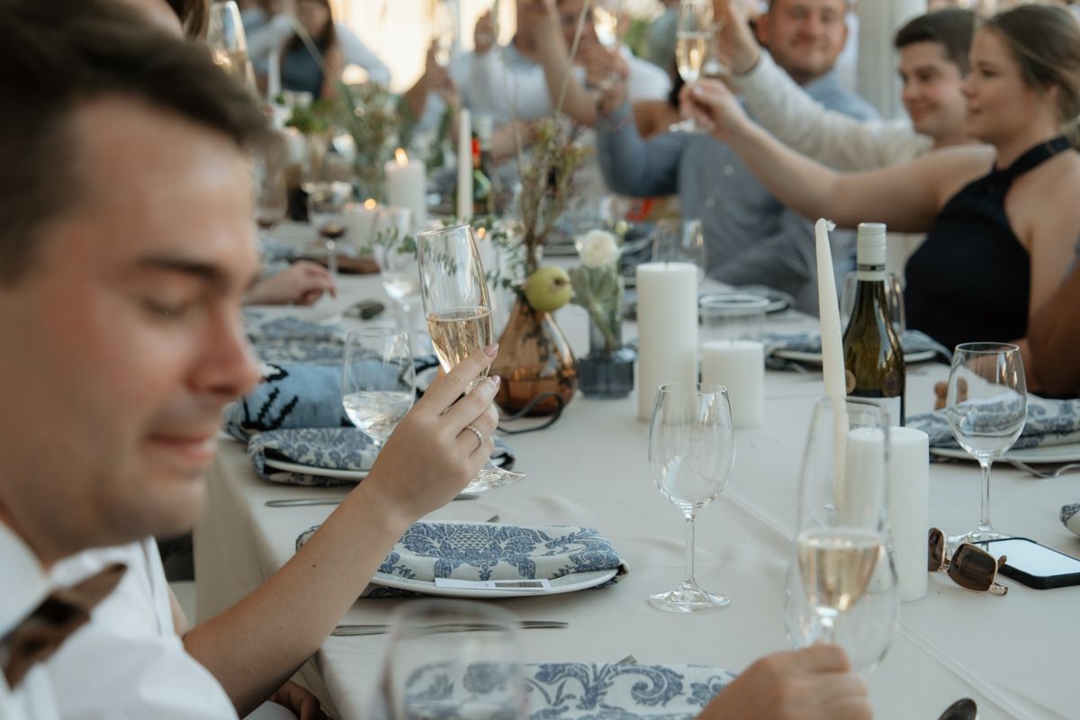 Wedding guests raising champagne glasses in a toast at an elegantly decorated reception dinner table.