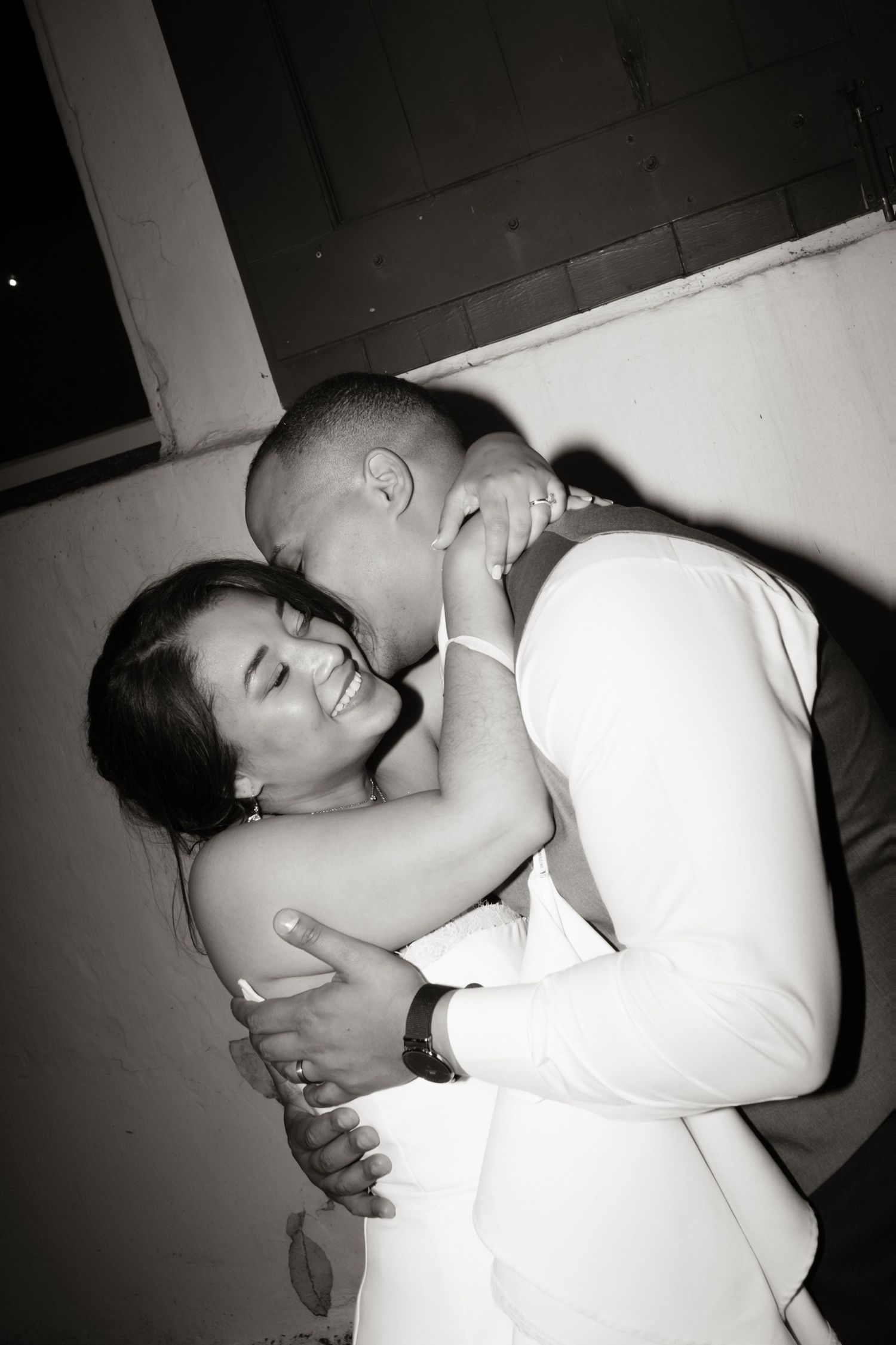 Black and white photo of bride and groom sharing an intimate embrace and dance at wedding reception.