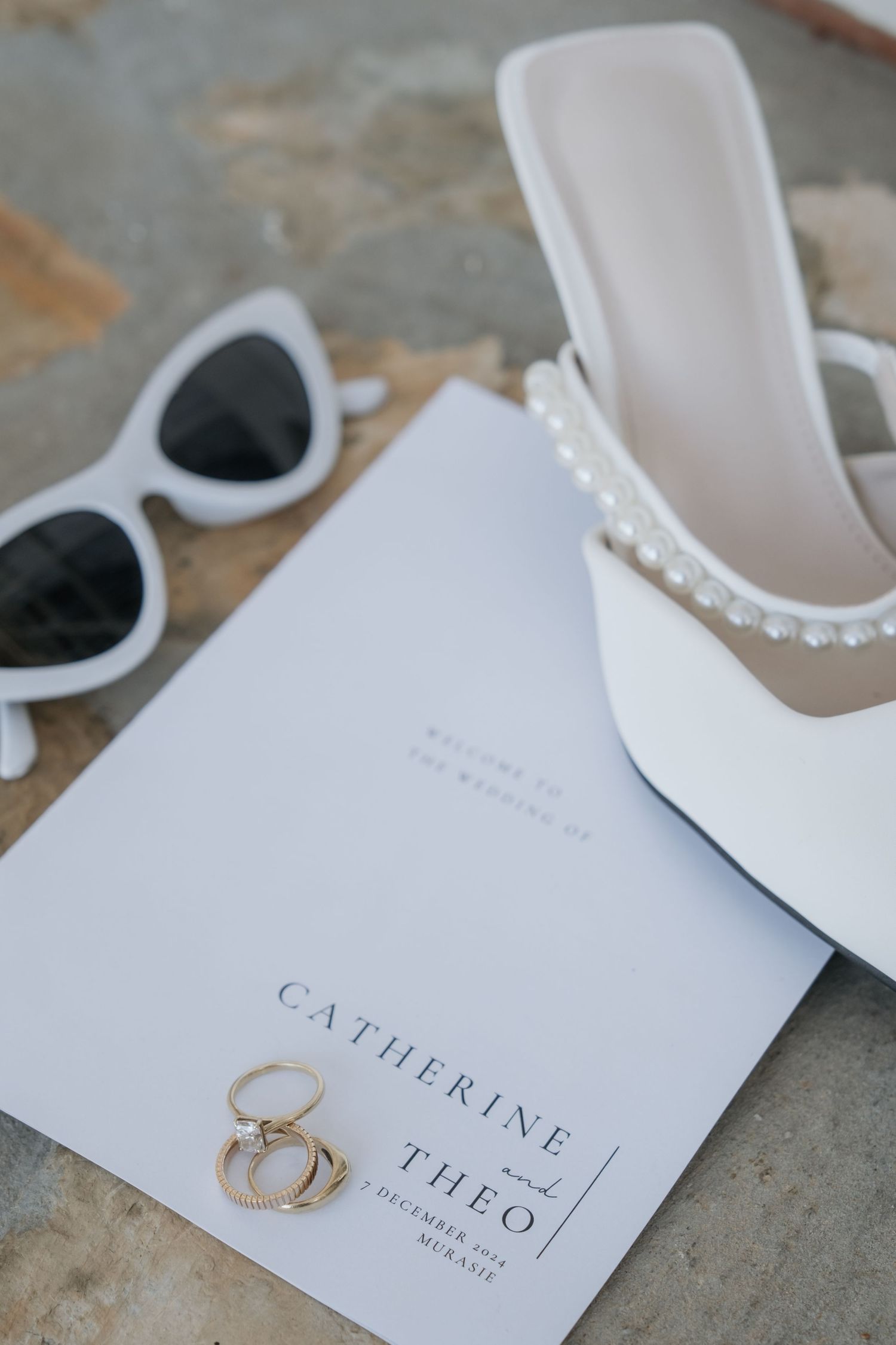 White bridal shoes and wedding stationery with elegant typography on a textured surface.