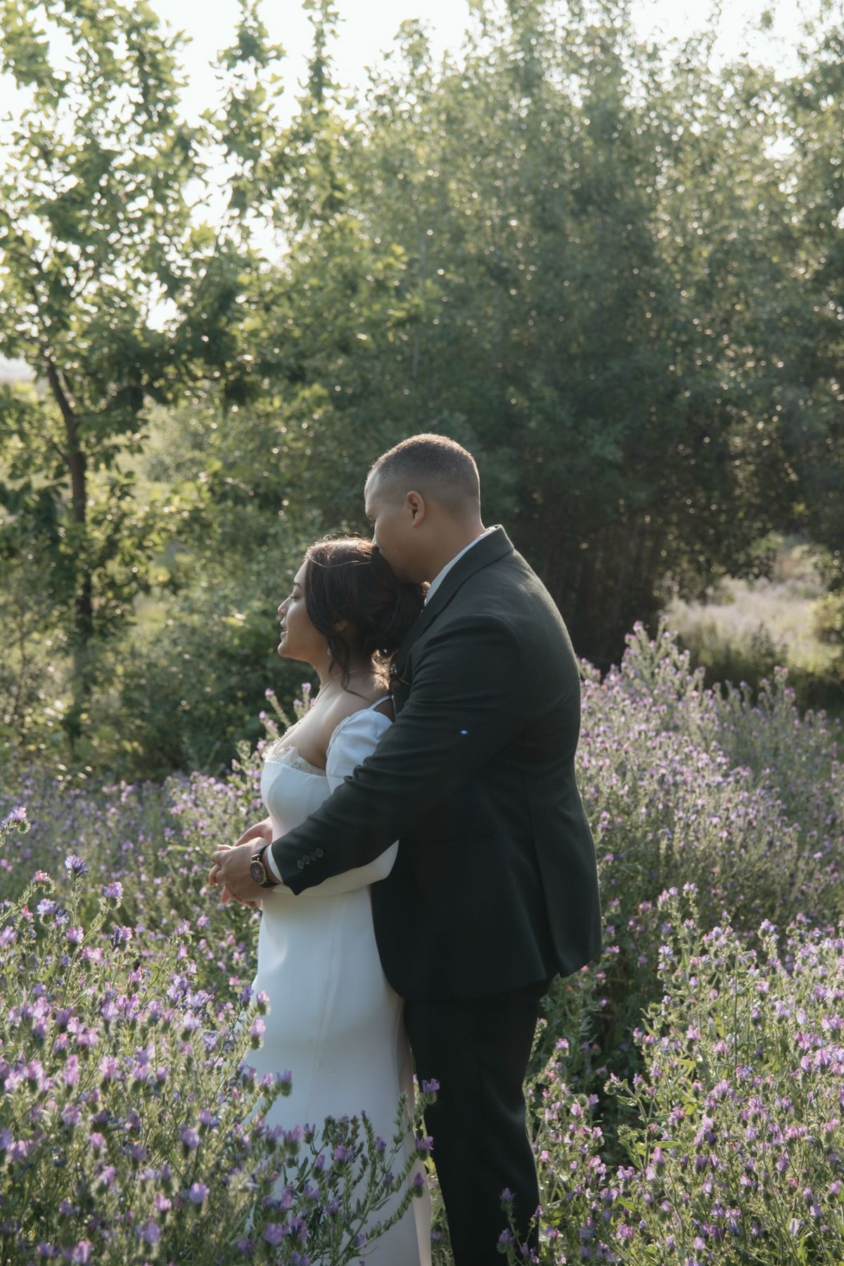Bride and groom embracing in lavender field at sunset.