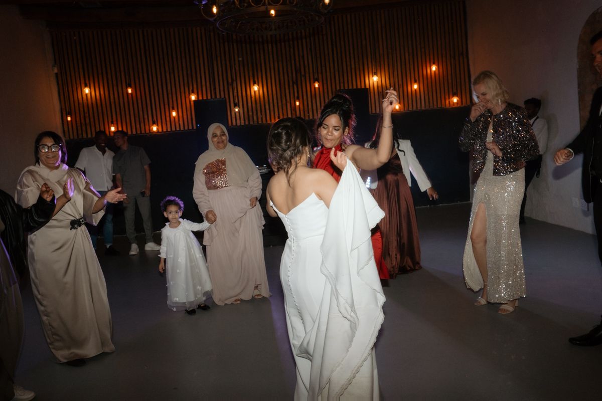 Bride in white strapless gown dancing and celebrating with female guests at lively wedding reception.