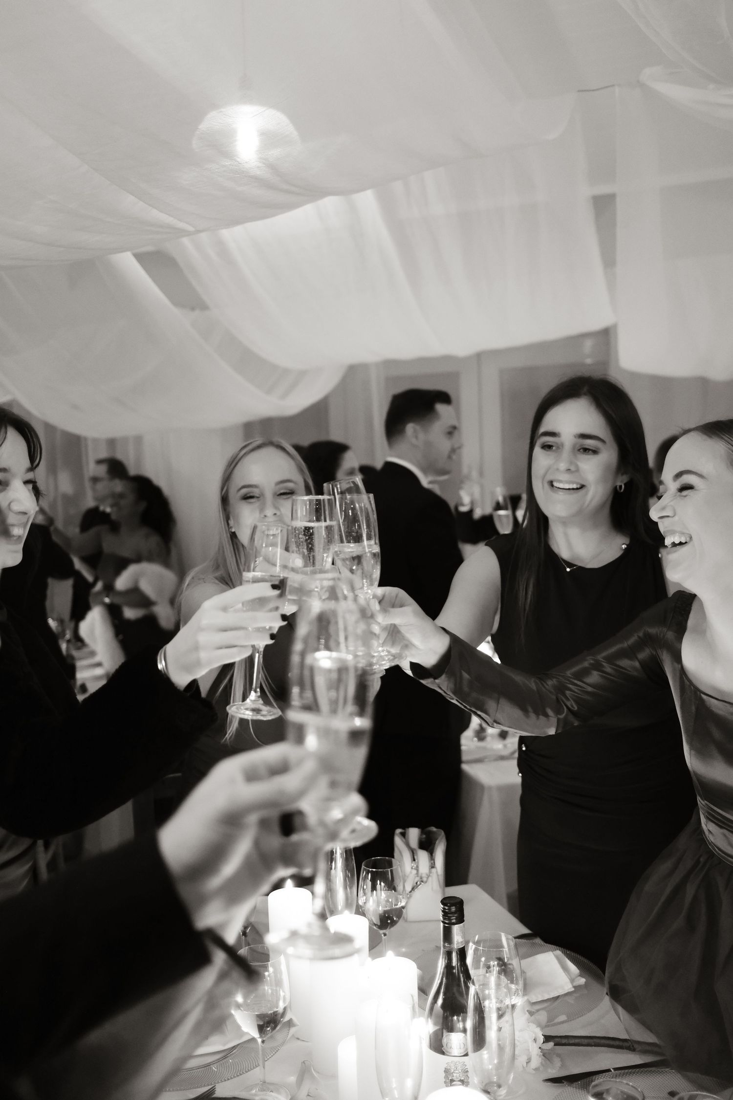 Wedding guests raise champagne glasses in joyful toast at elegant indoor reception celebration.