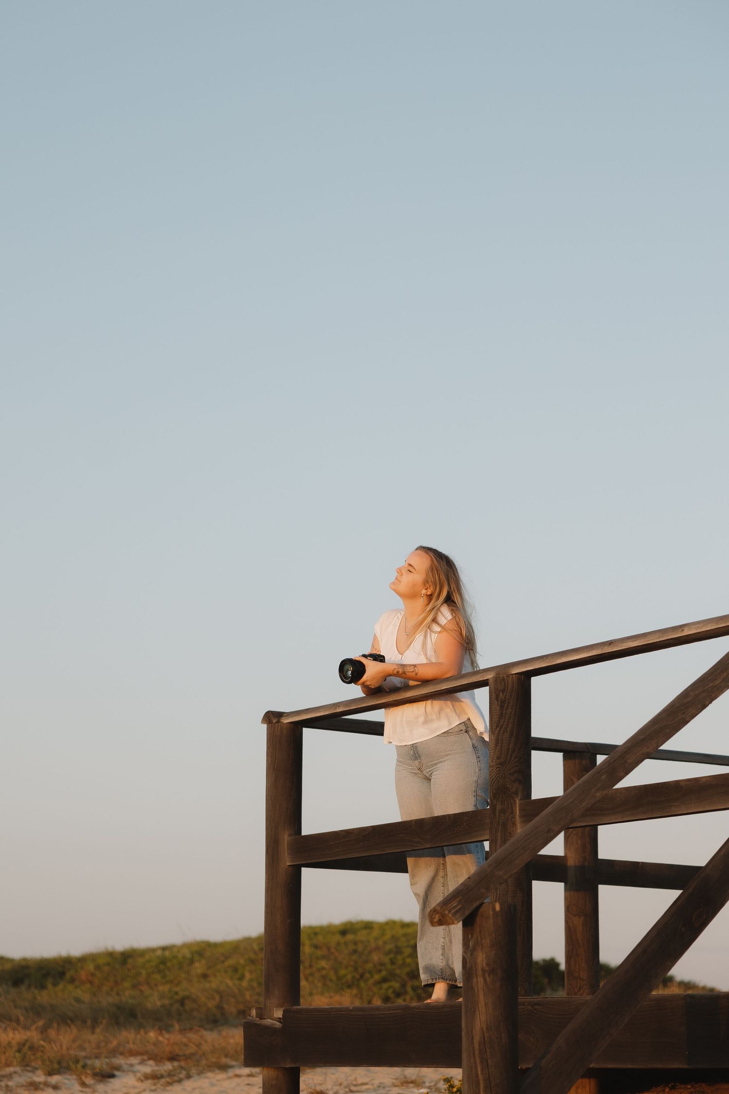 Cape Town Photographer standing on wooden deck overlooking beach at sunset.