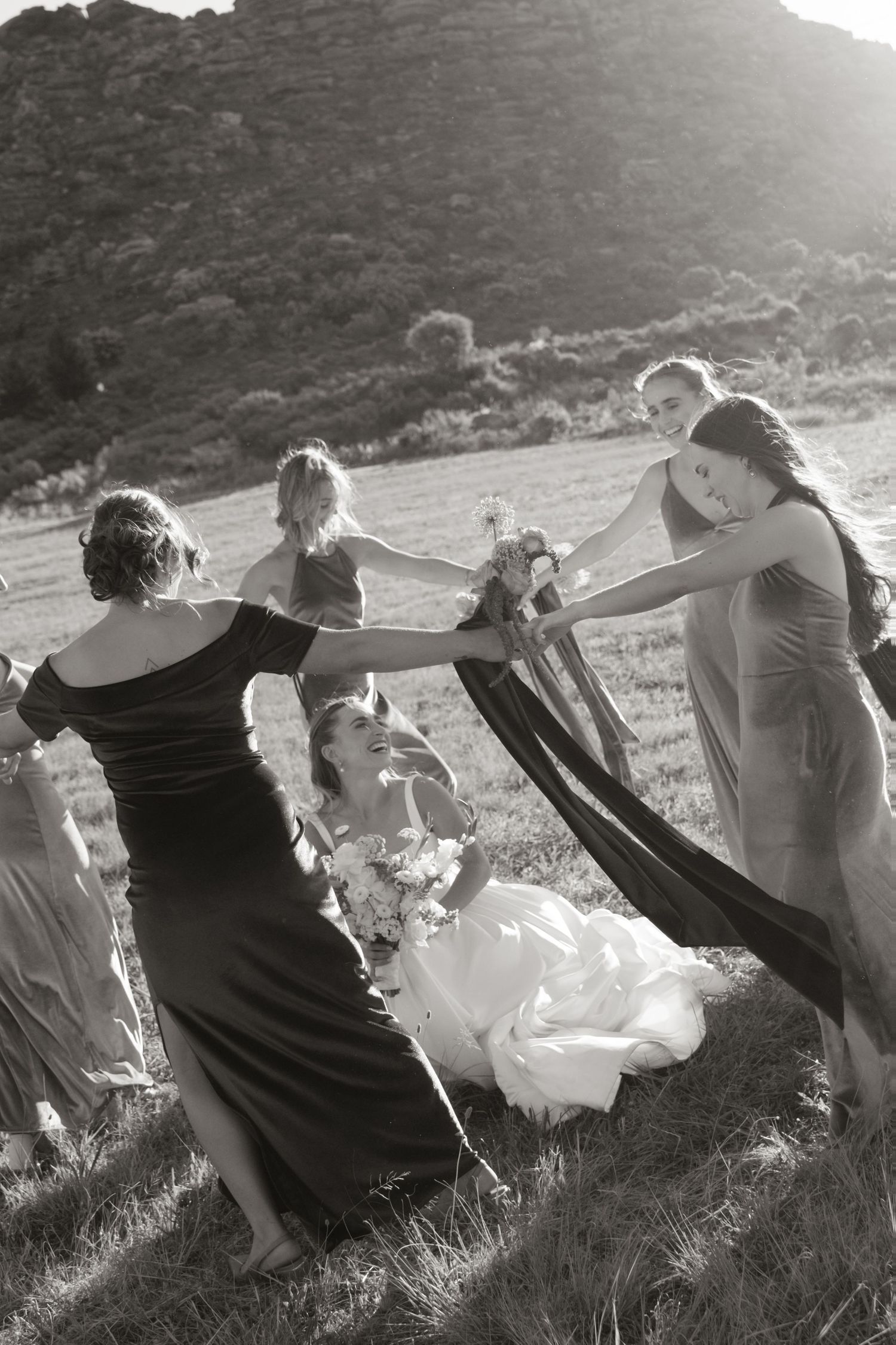 Black and white sequence of people on a grassy hillside with flowing fabric in the wind.