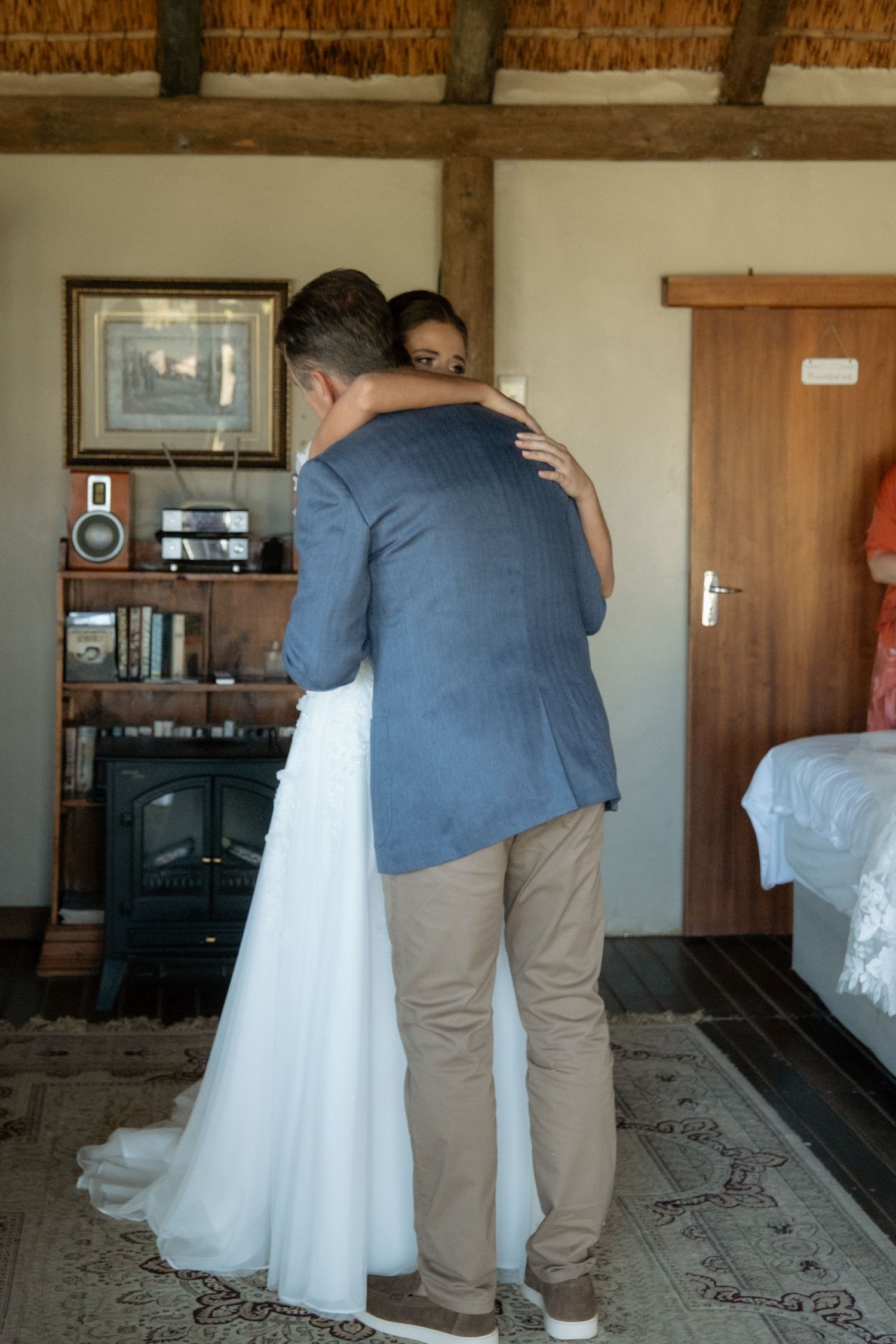 Bride and groom sharing a tender embrace inside a rustic lodge room on their wedding day.