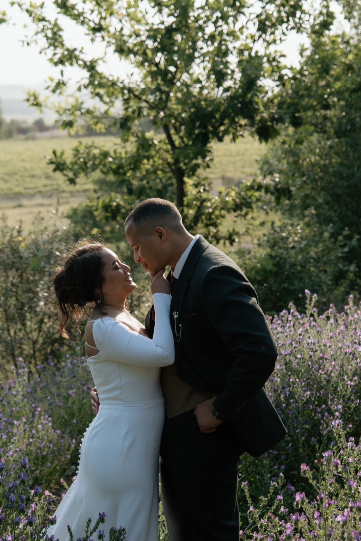 Bride and groom embracing romantically in a purple lavender field at golden hour.