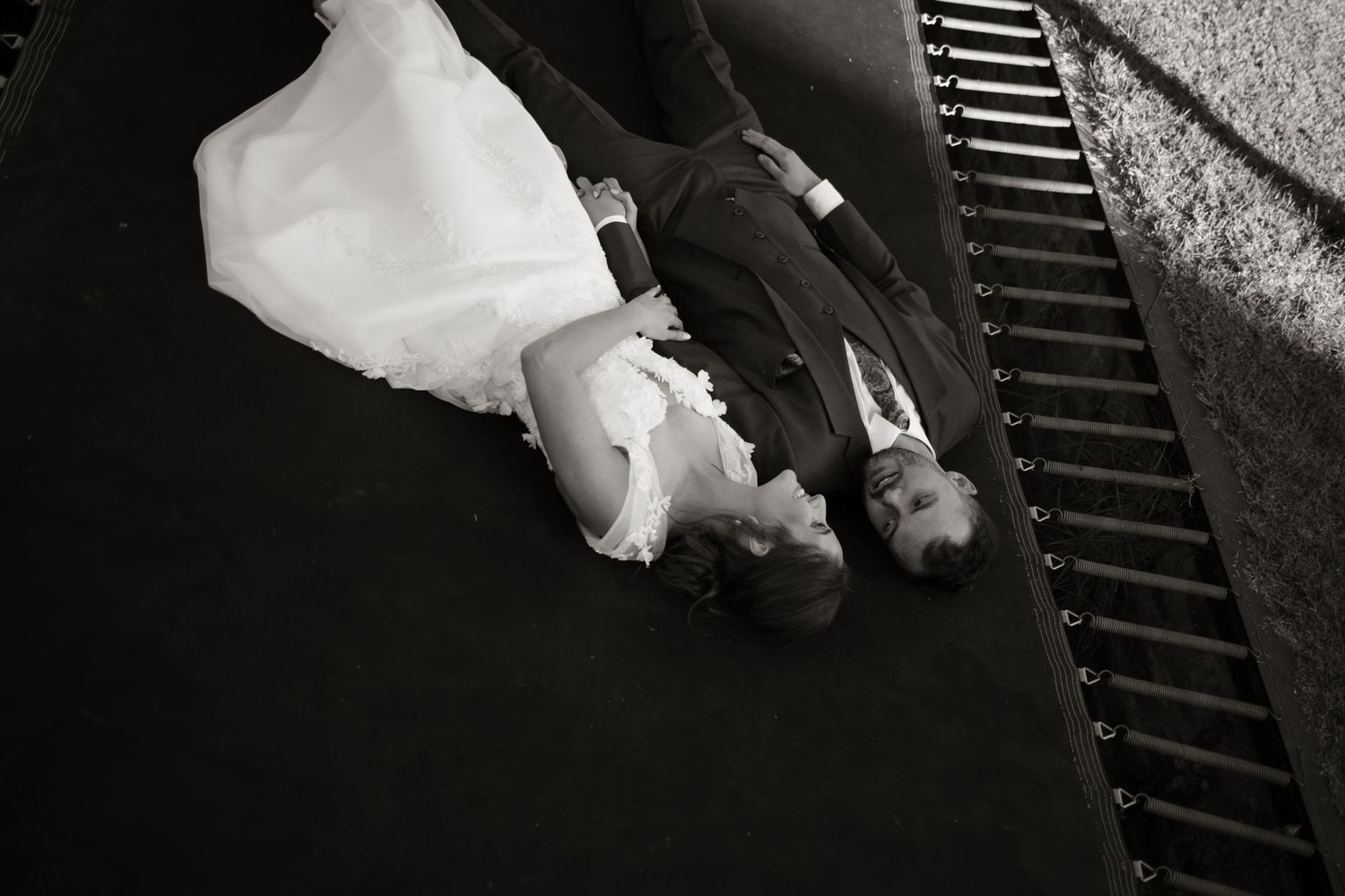 Artistic black and white aerial shot of bride and groom lying on steps at their wedding.