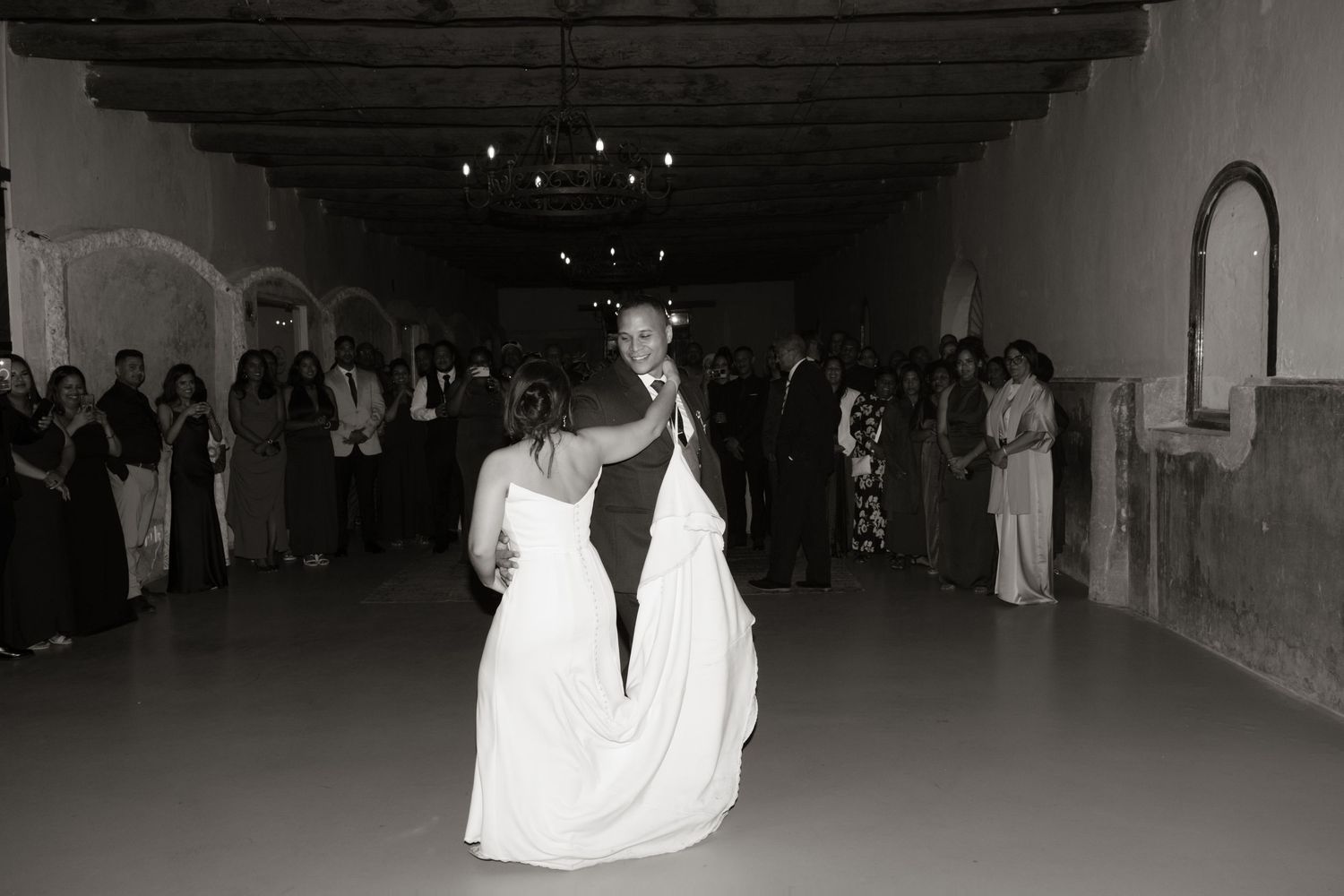 Black and white photo of bride and groom sharing their first dance at reception.