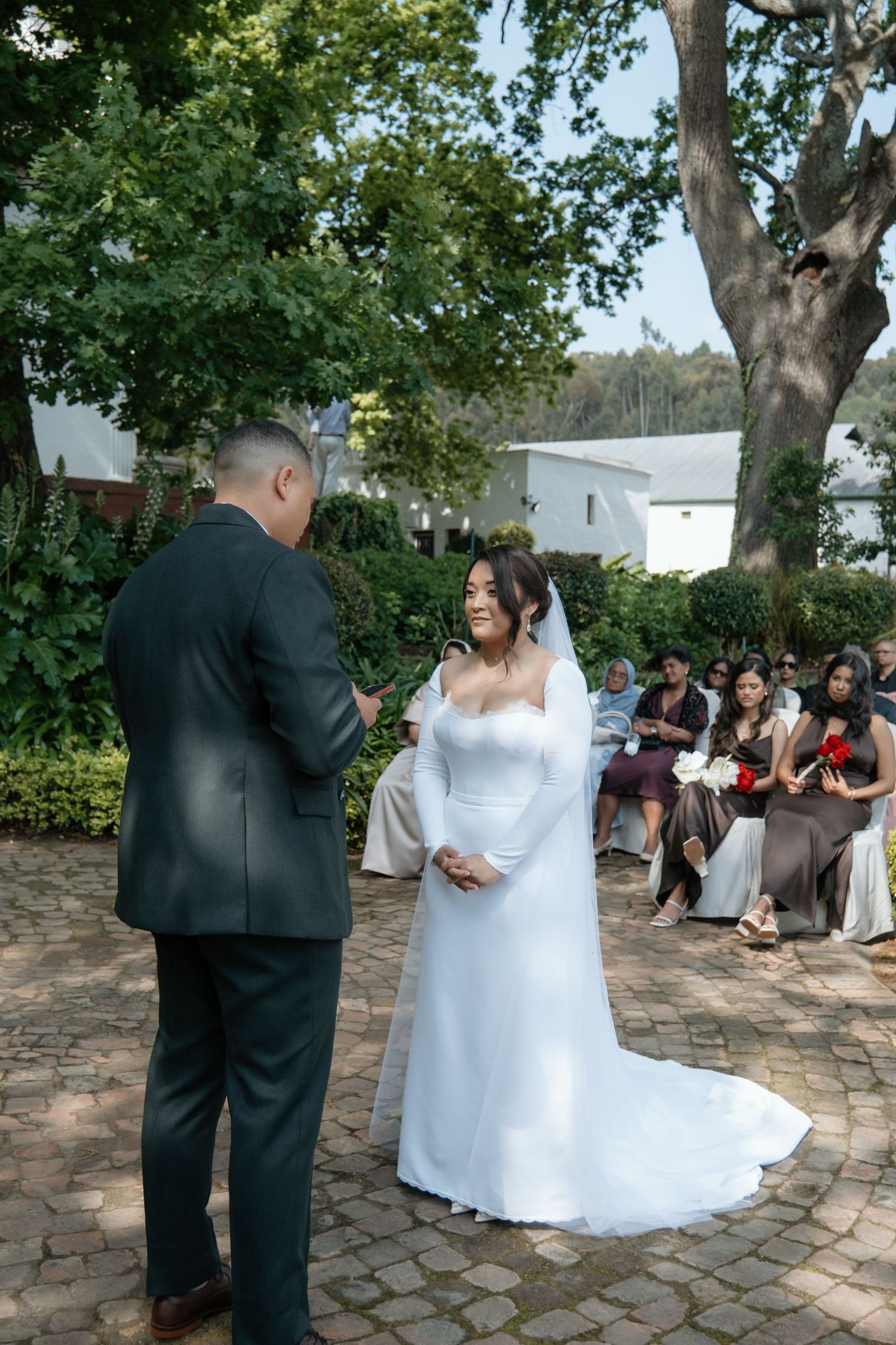 Bride and groom exchanging vows at an outdoor garden wedding ceremony.