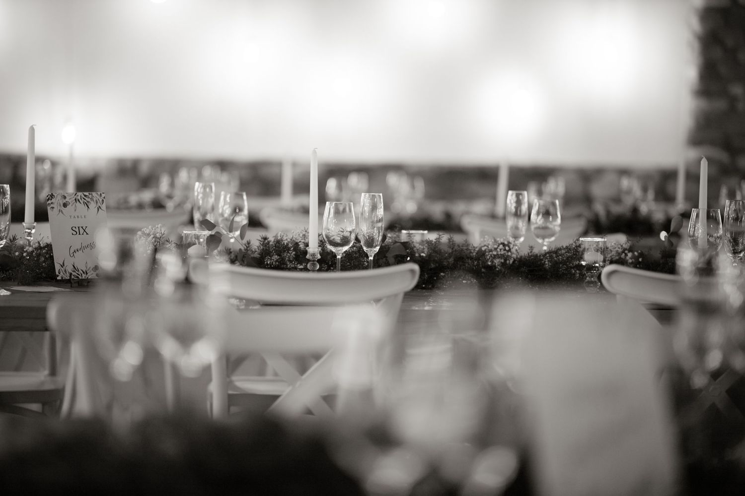 Elegant black and white wedding reception table setting with crystal glasses, candles, and floral centerpieces.