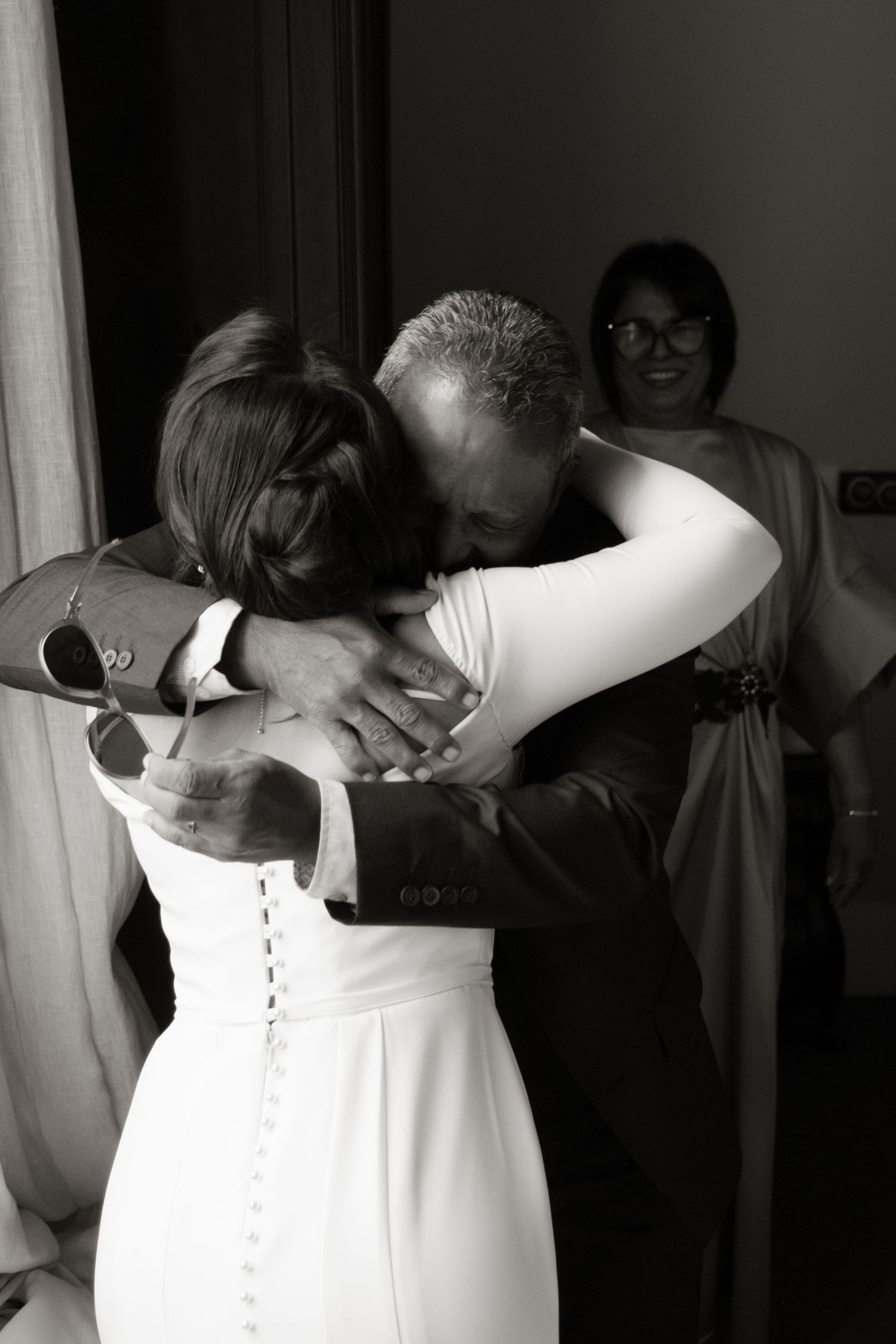 Emotional black and white photo of a bride and father sharing a tender hug before the wedding ceremony.