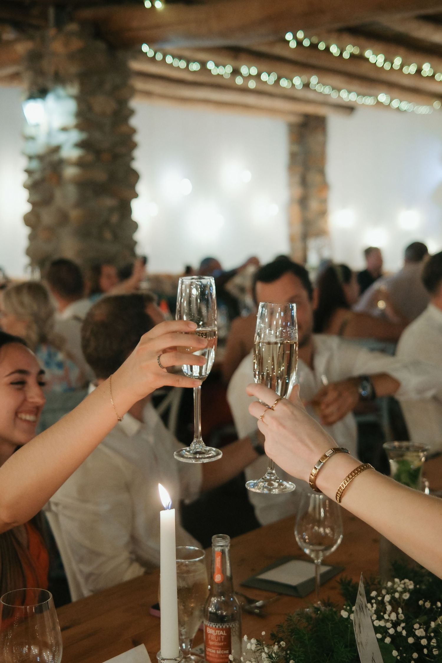 Guests clinking champagne flutes in a toast at an elegant candlelit wedding reception.