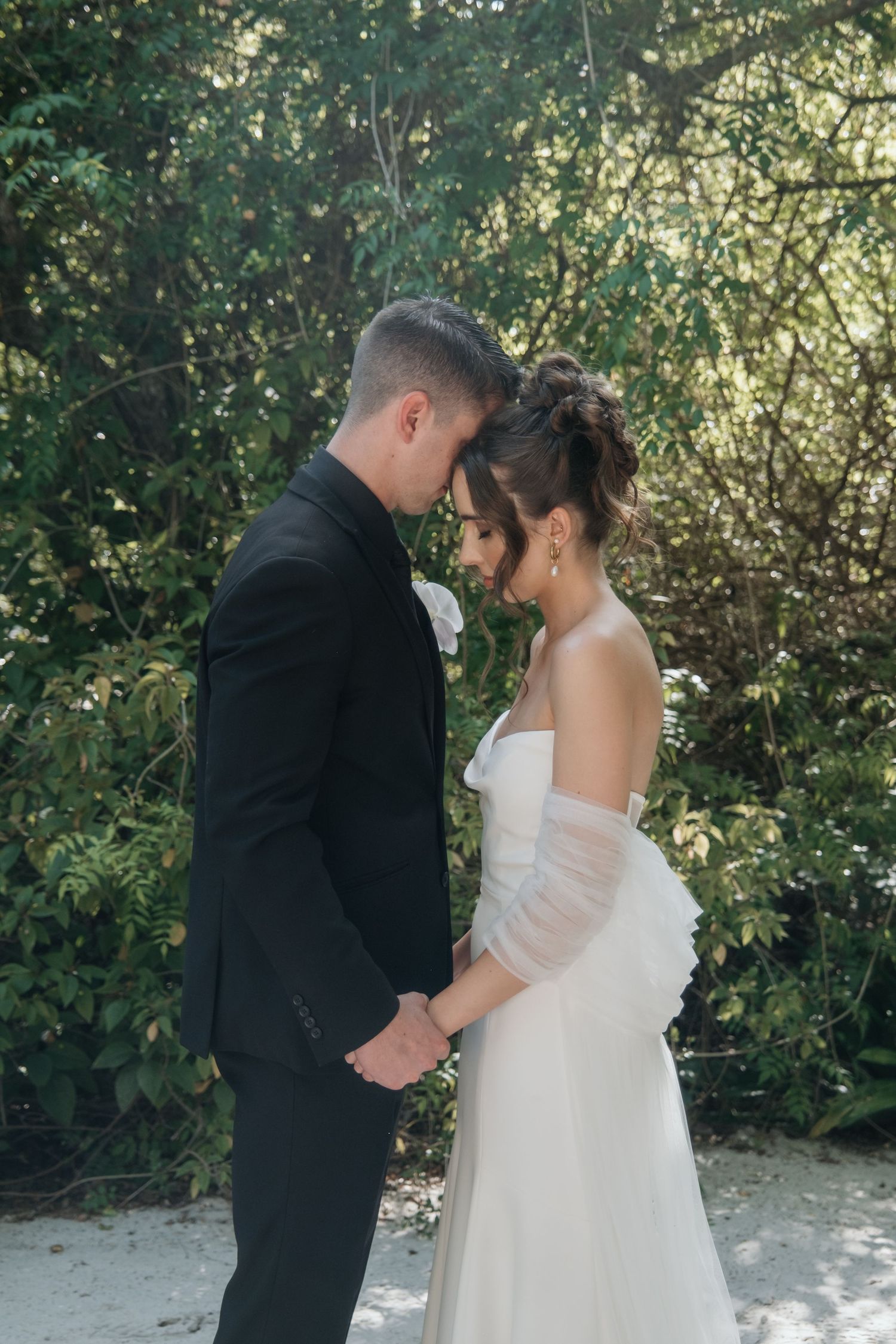 A couple shares an intimate moment in a garden setting during their wedding first look photo session.