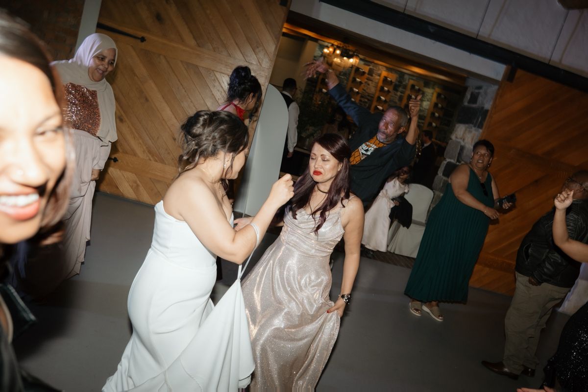 Wedding guests dancing and celebrating energetically on the dance floor during lively evening reception party.