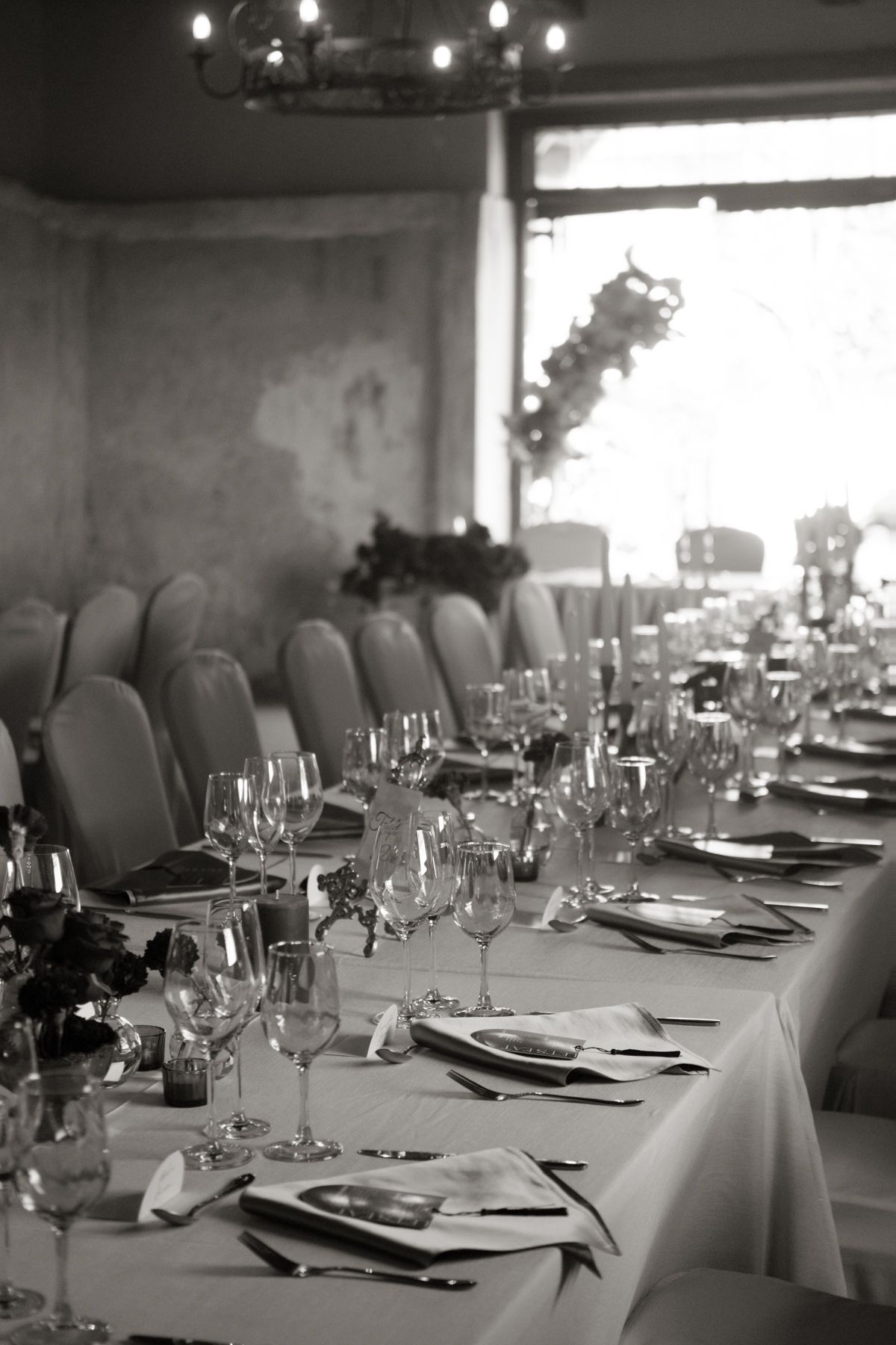 Black and white image of elegant wedding reception table with crystal glasses and floral arrangements.
