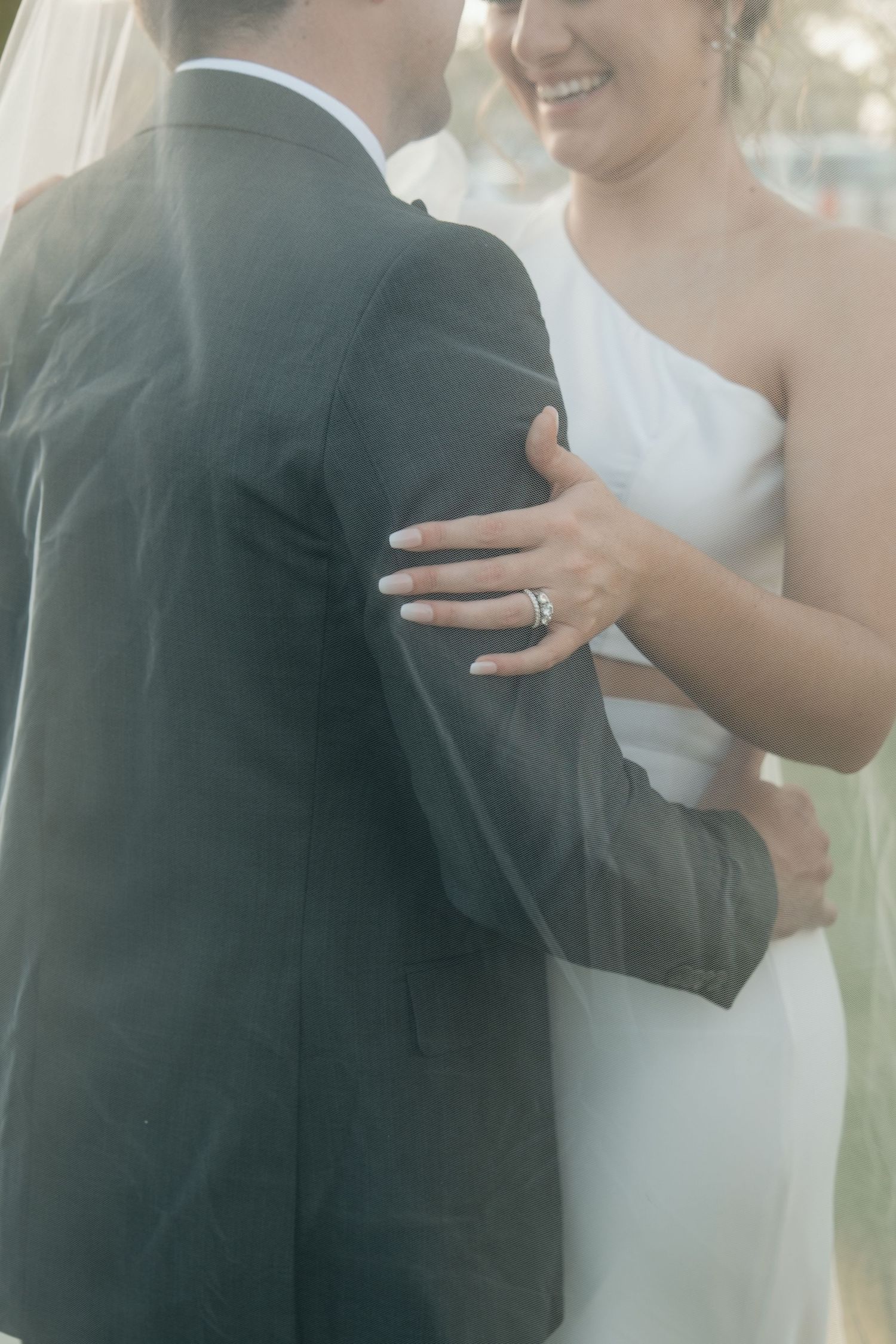 Close up of newlyweds embracing showing diamond ring.