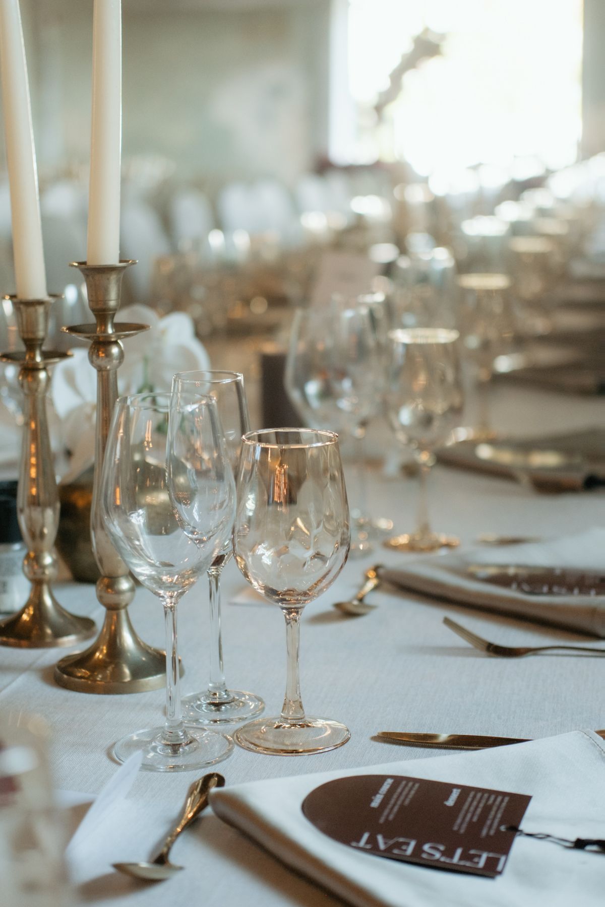 Sophisticated wedding table setting featuring crystal glassware, silver candlesticks, and white linens.