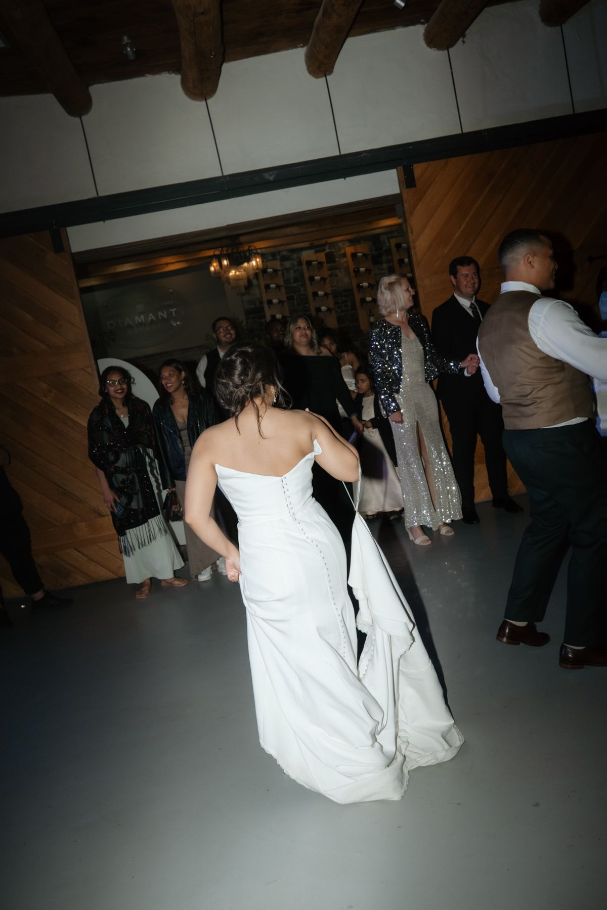 Bride in a white strapless gown dancing on the floor surrounded by wedding guests.
