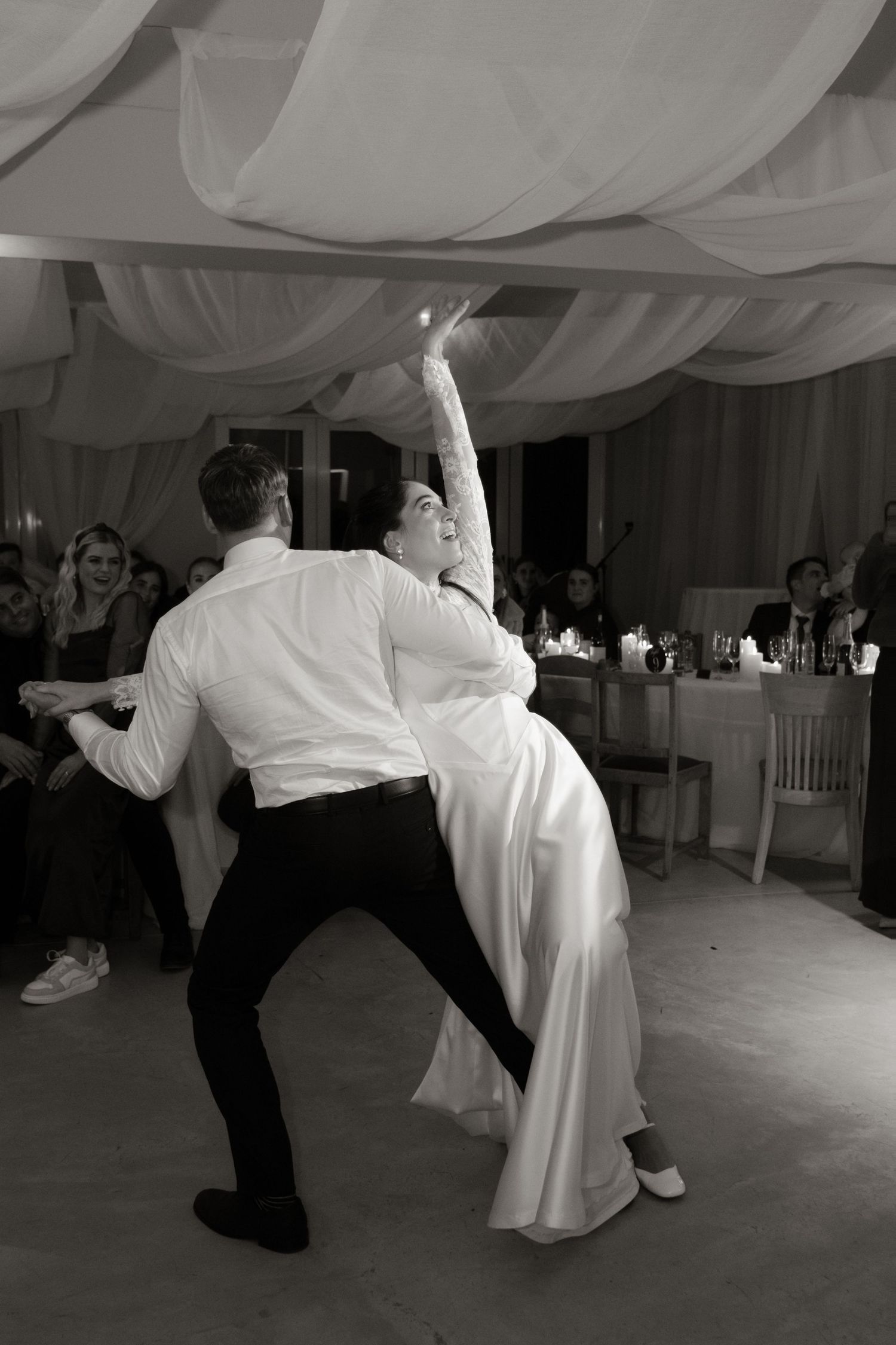 Black and white photo of bride and groom performing dramatic first dance at wedding reception.