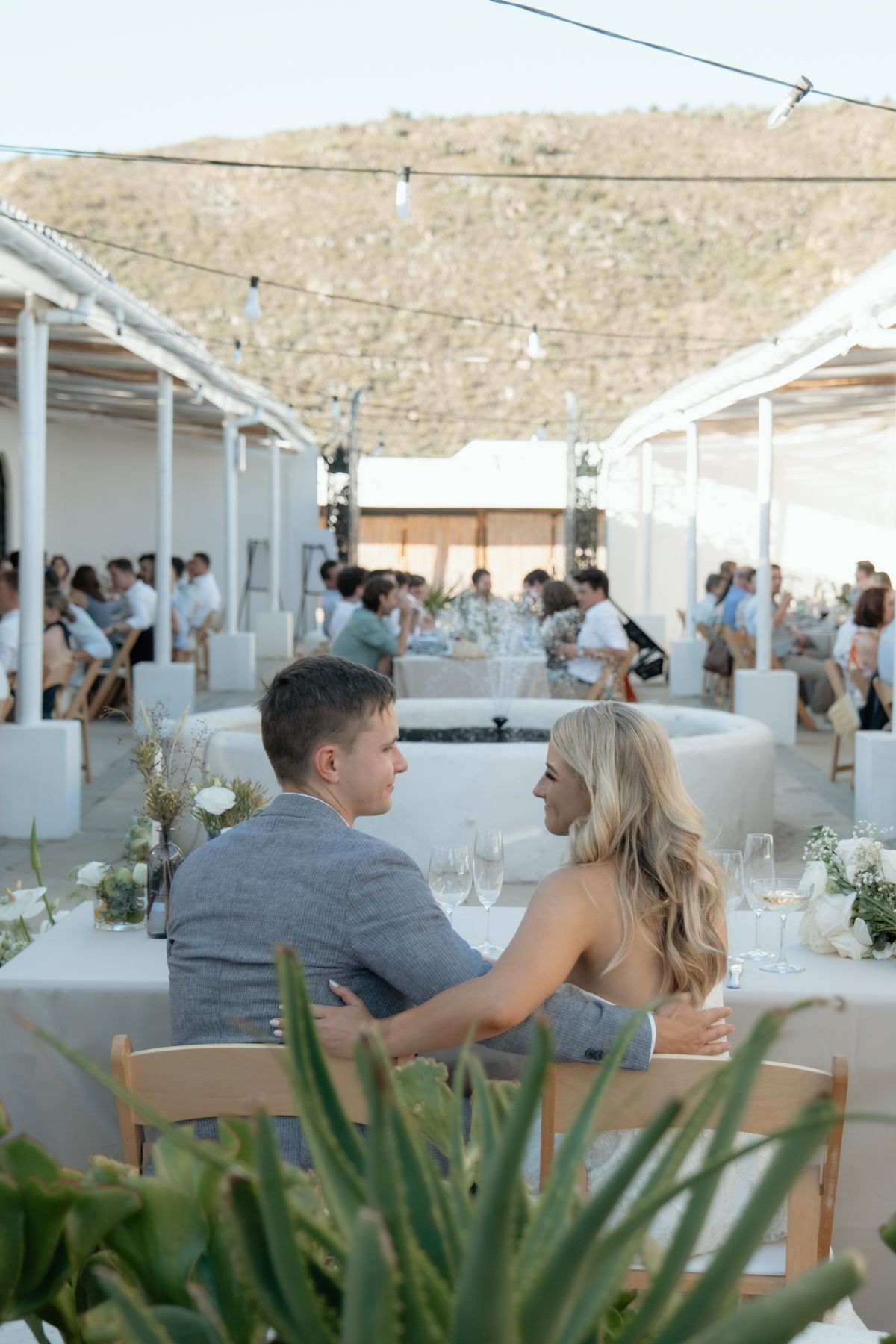 Couple sharing an intimate moment at an outdoor wedding reception in a whitewashed Mediterranean venue.
