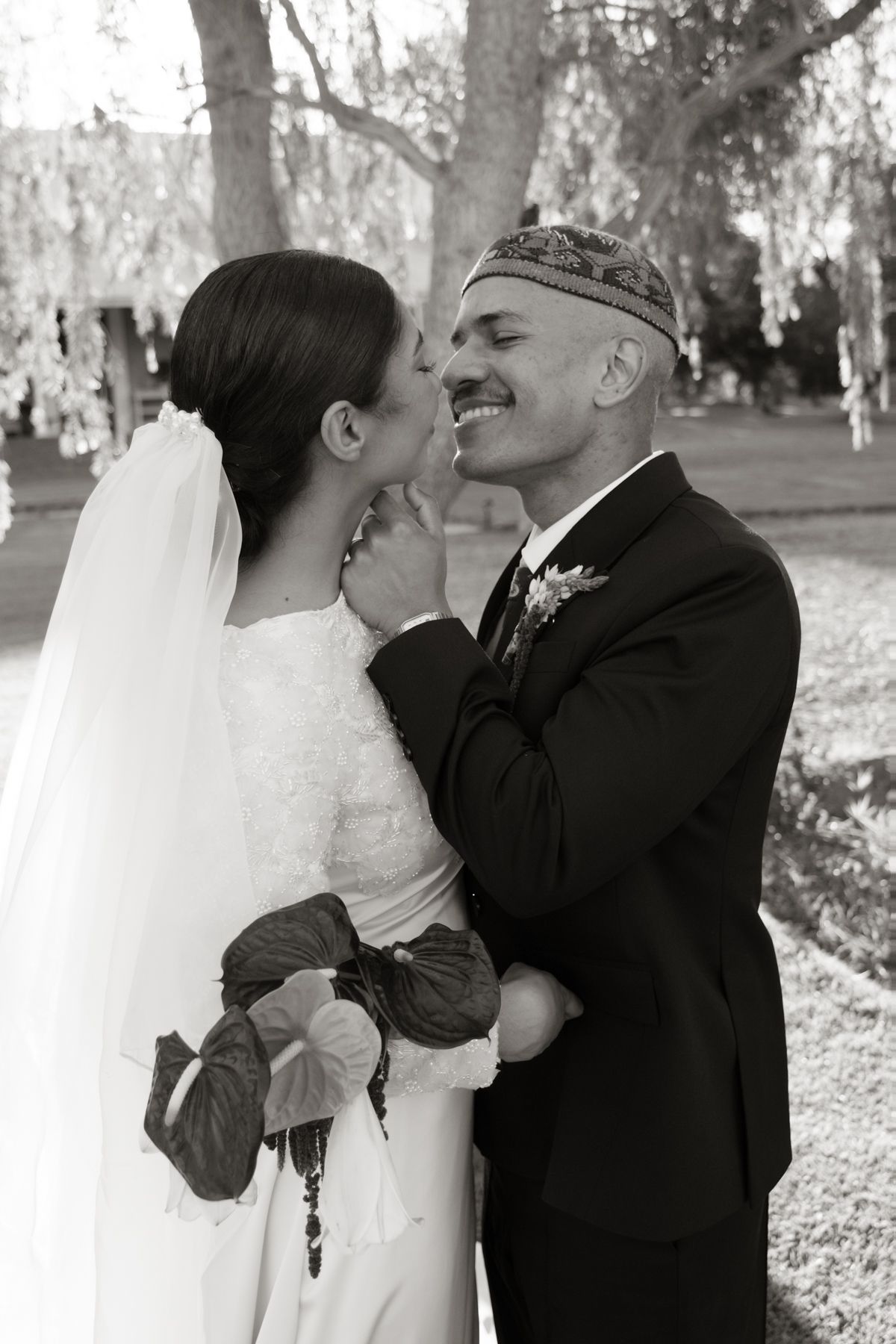 Black and white photo of smiling bride and groom sharing a tender moment at their outdoor wedding.