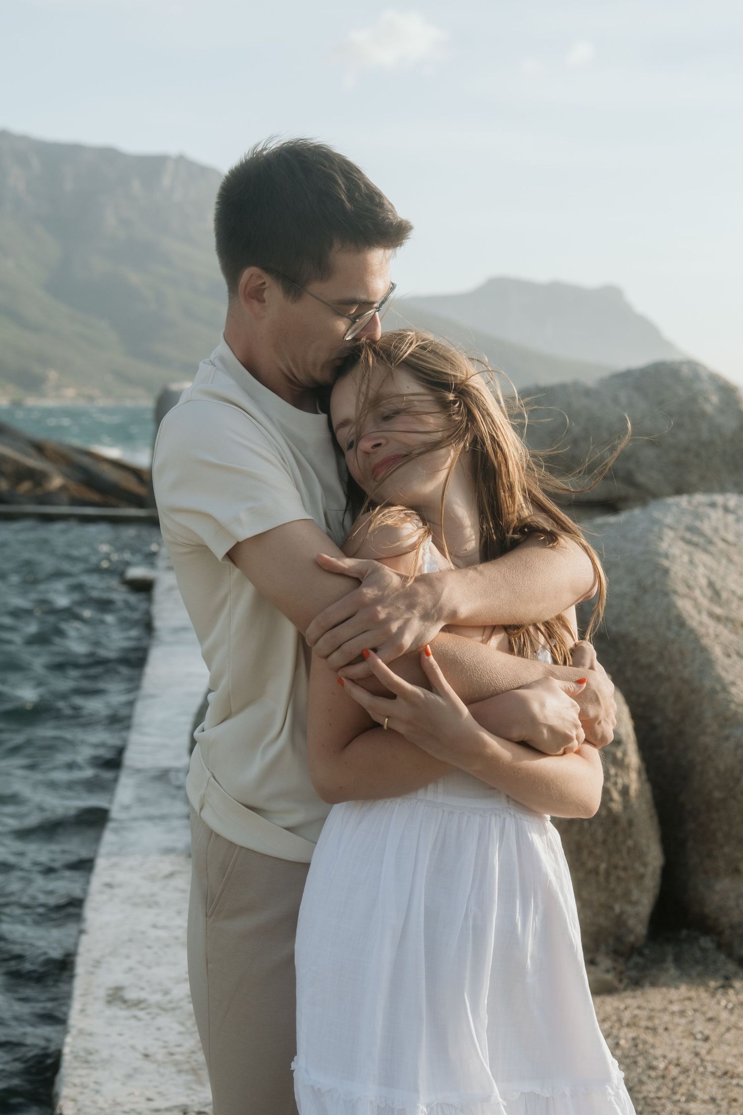 Intimate embrace by the ocean with Camps Bay mountains in background.
