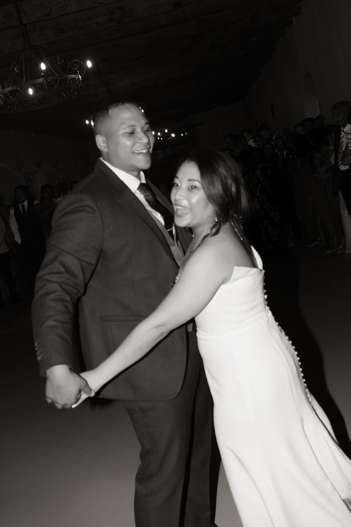 Bride and groom smiling during first dance in black and white.