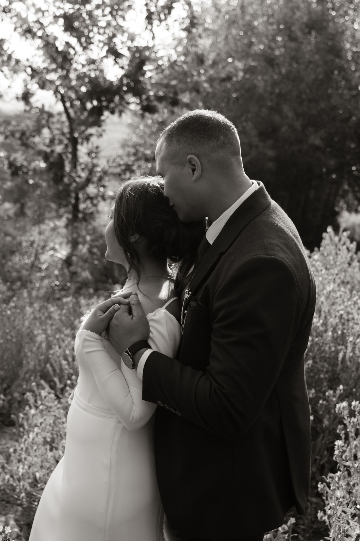 Black and white photo of bride and groom sharing a tender kiss outdoors.