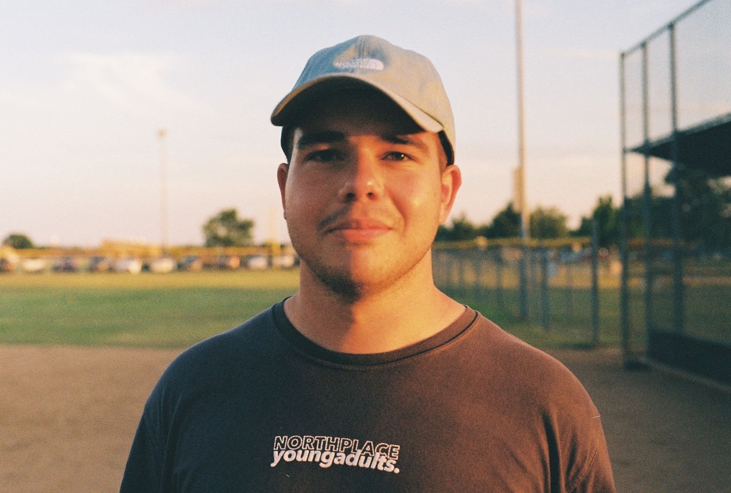 Man on baseball field with a sun-glow on his face smiling