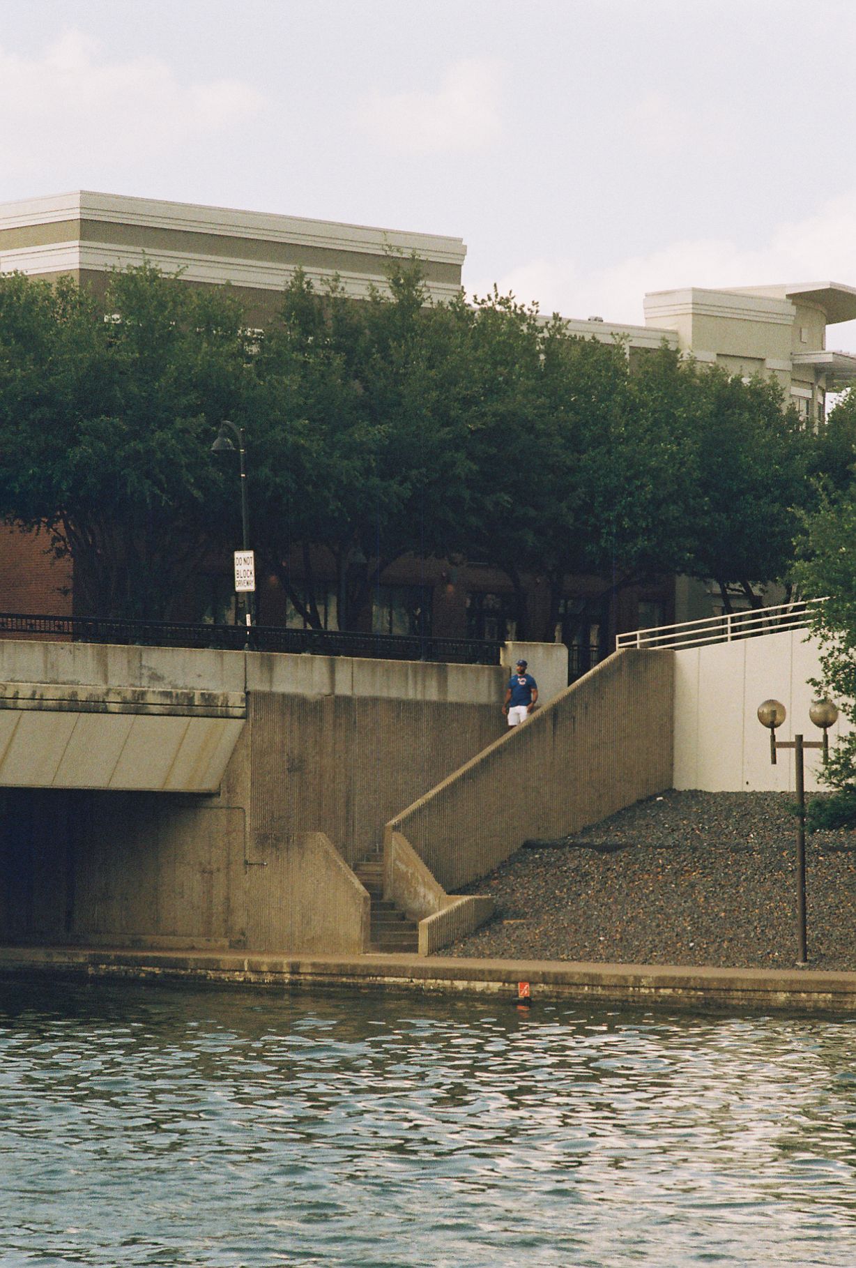 Image of stairs across a body of water. There is a man in a blue shirt walking down the stairs