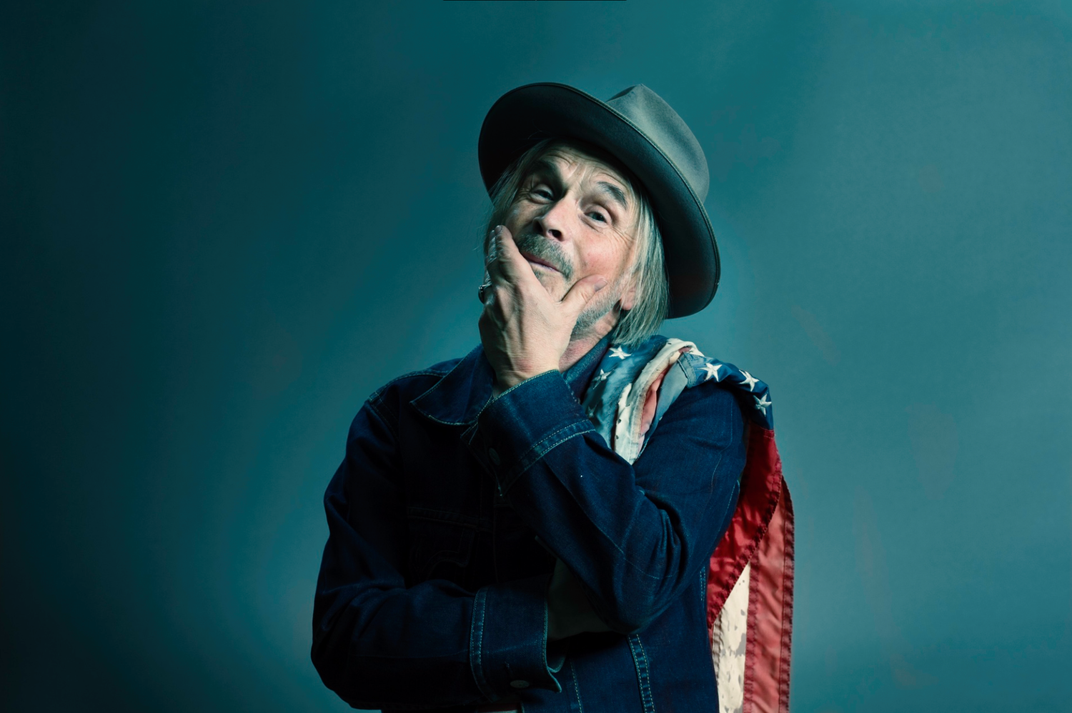 Artistic portrait with moody teal lighting and vintage hat styling.